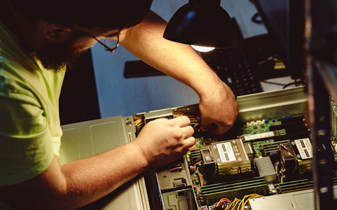 Man repairing a computer server under a lamp.