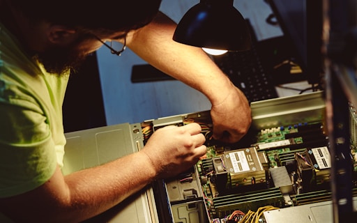 Man repairing a computer server under a lamp.