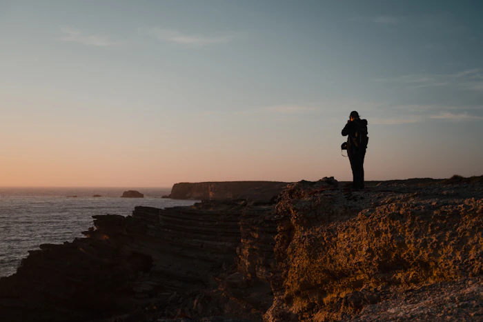 Traveler photographing Portugal coastline at sunset