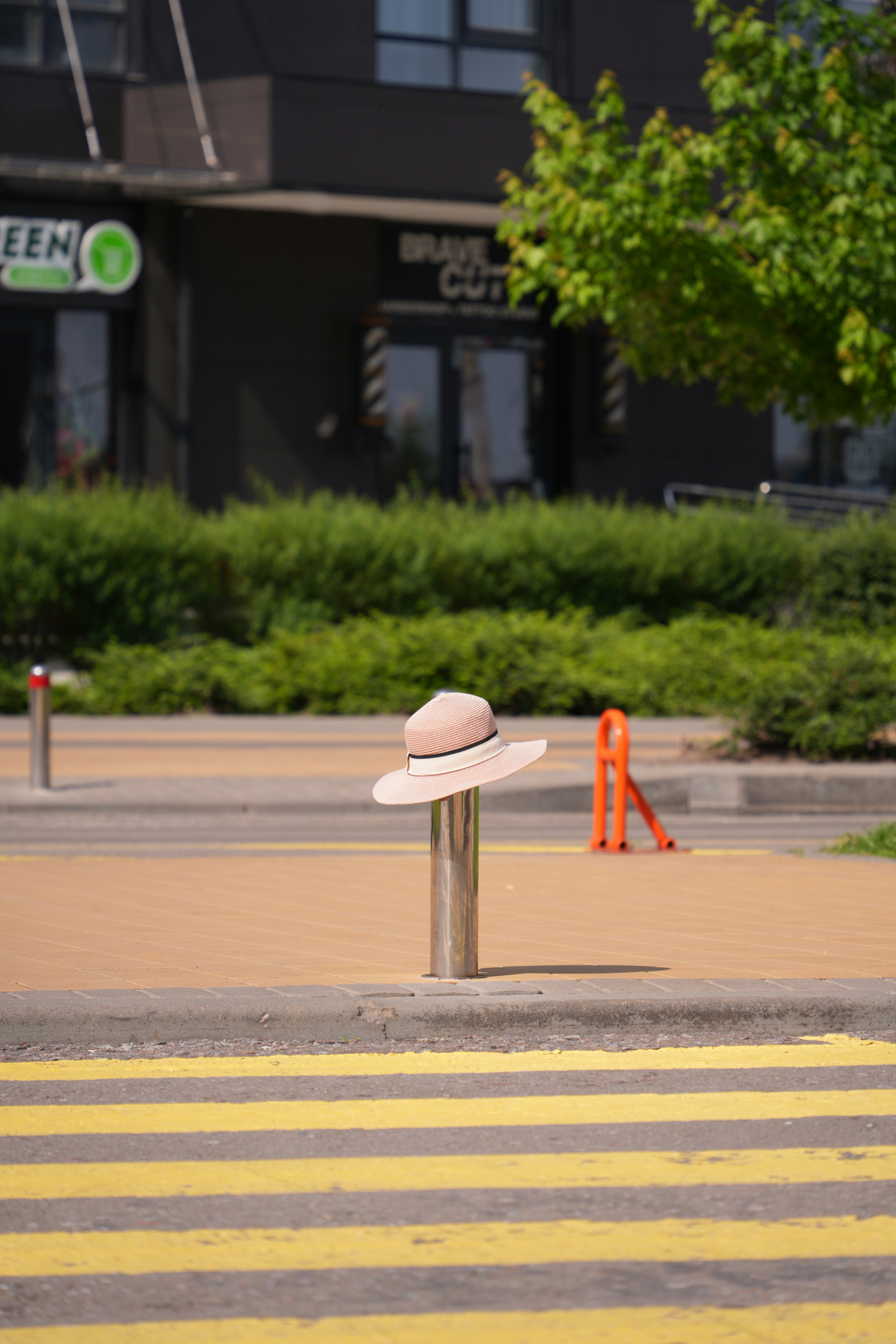 A hat rests on a pole in the street.