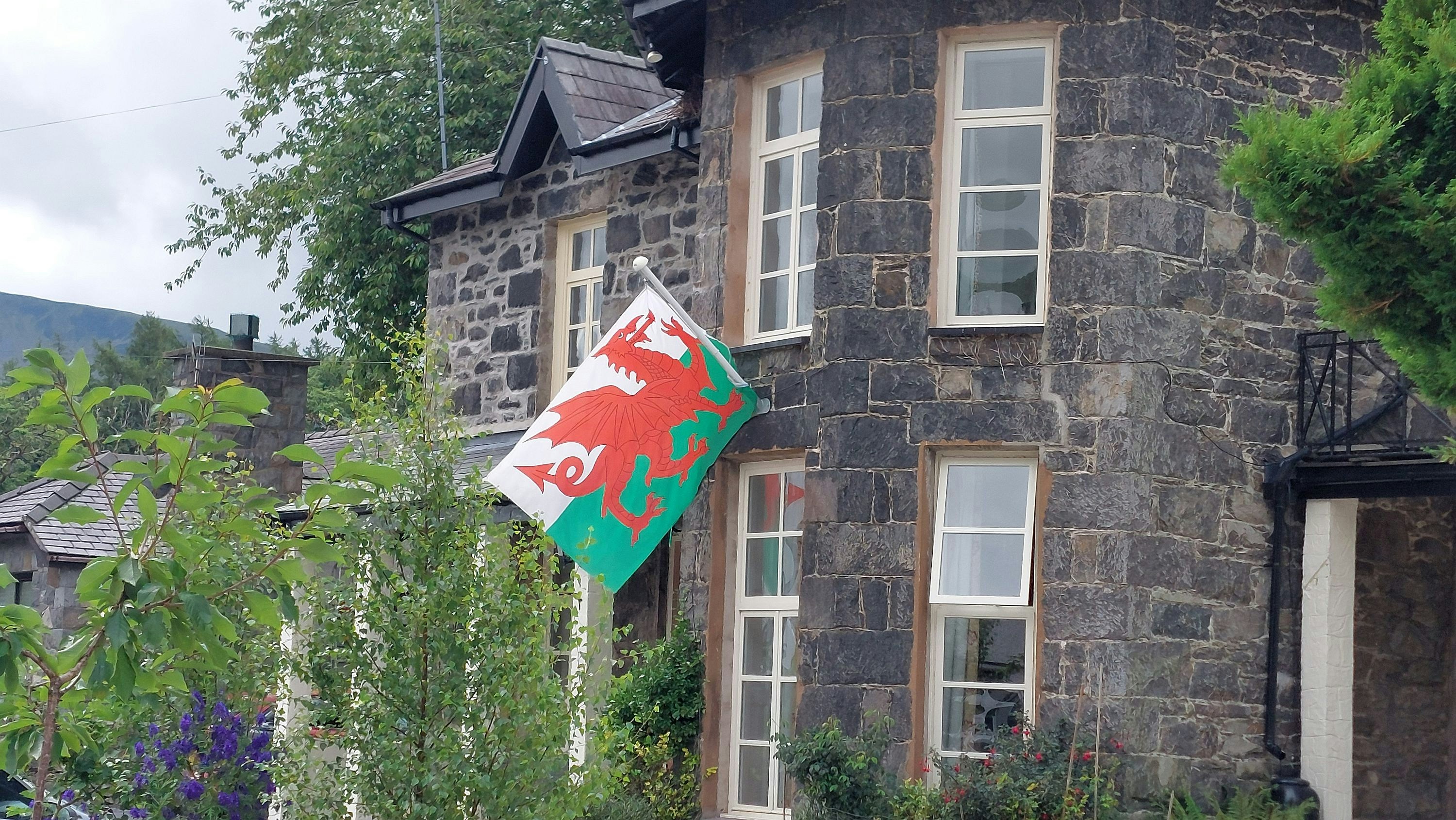 A welsh flag hangs outside a stone building.