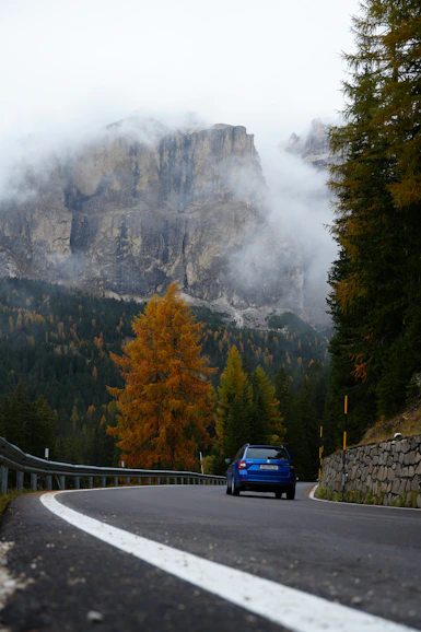 A car drives along a road in mountainous terrain