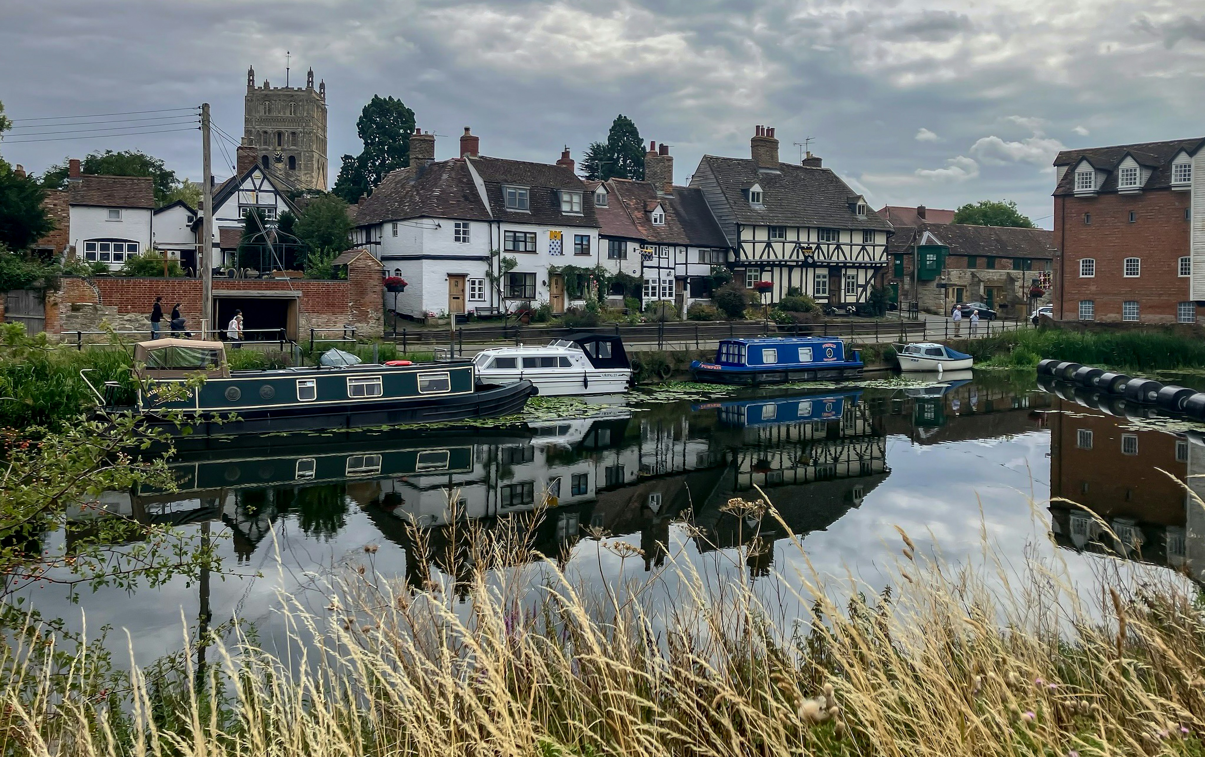 Boats and buildings reflect in calm, rippled water.