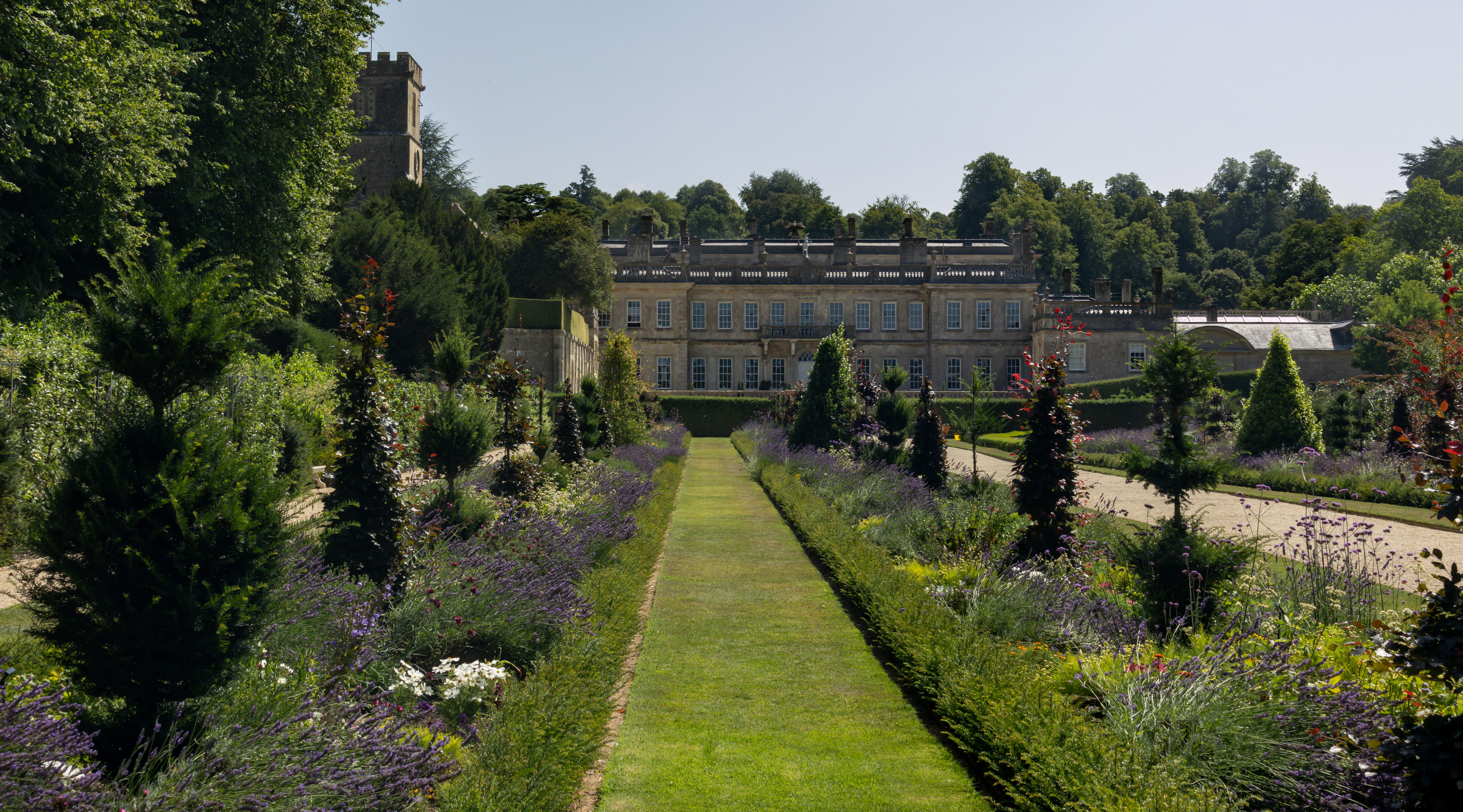 A beautiful garden leads to a stately home.
