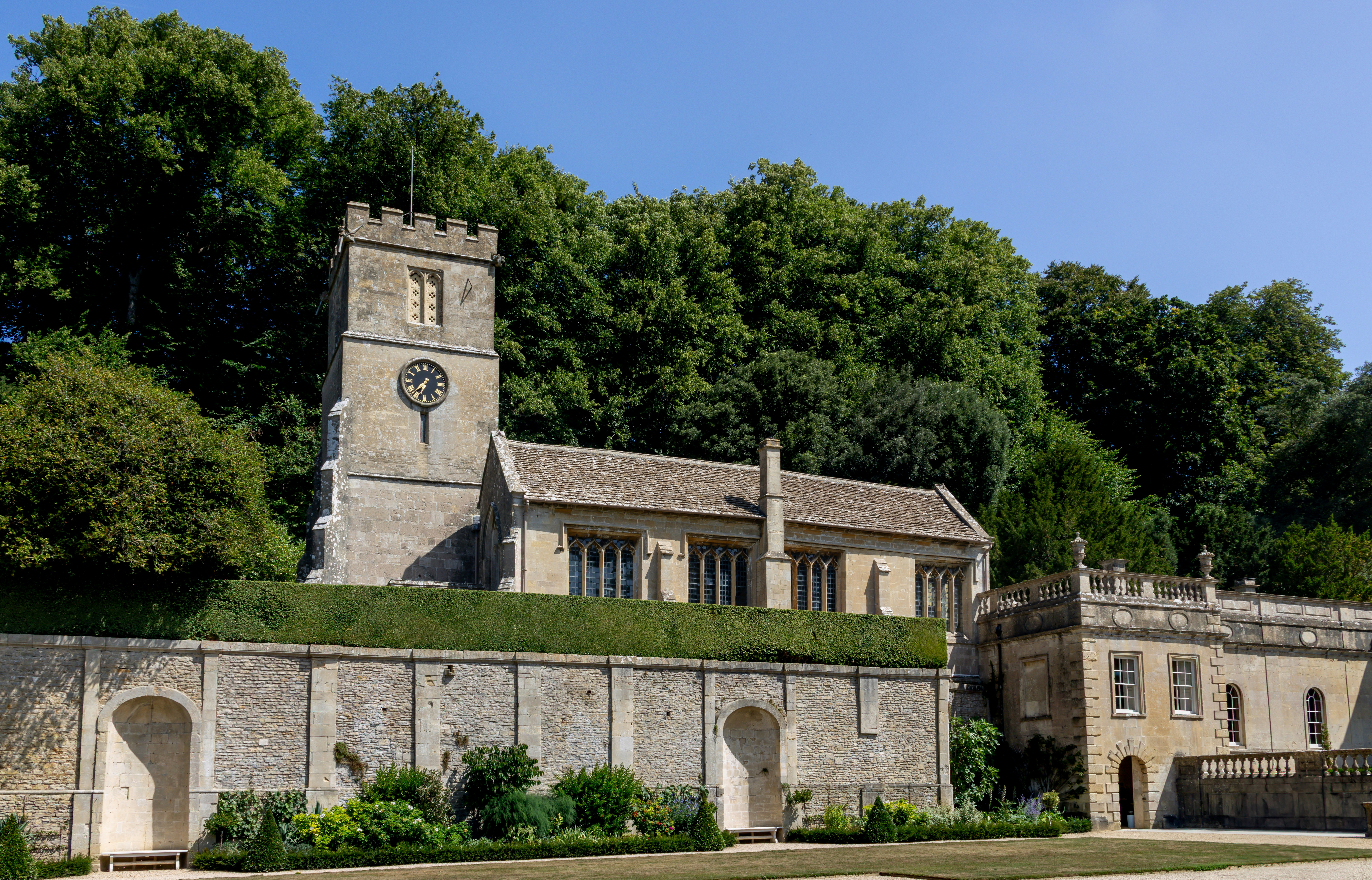 An old church sits nestled amongst green trees.