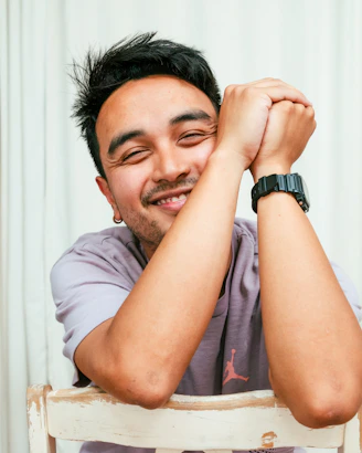 A smiling man with hands clasped on his head