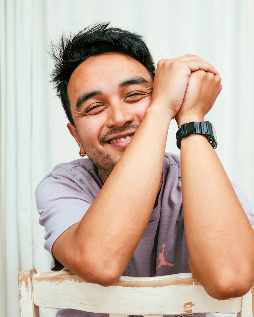 A smiling man with hands clasped on his head