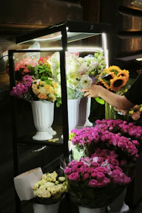 A person arranges flowers in a brightly lit display.