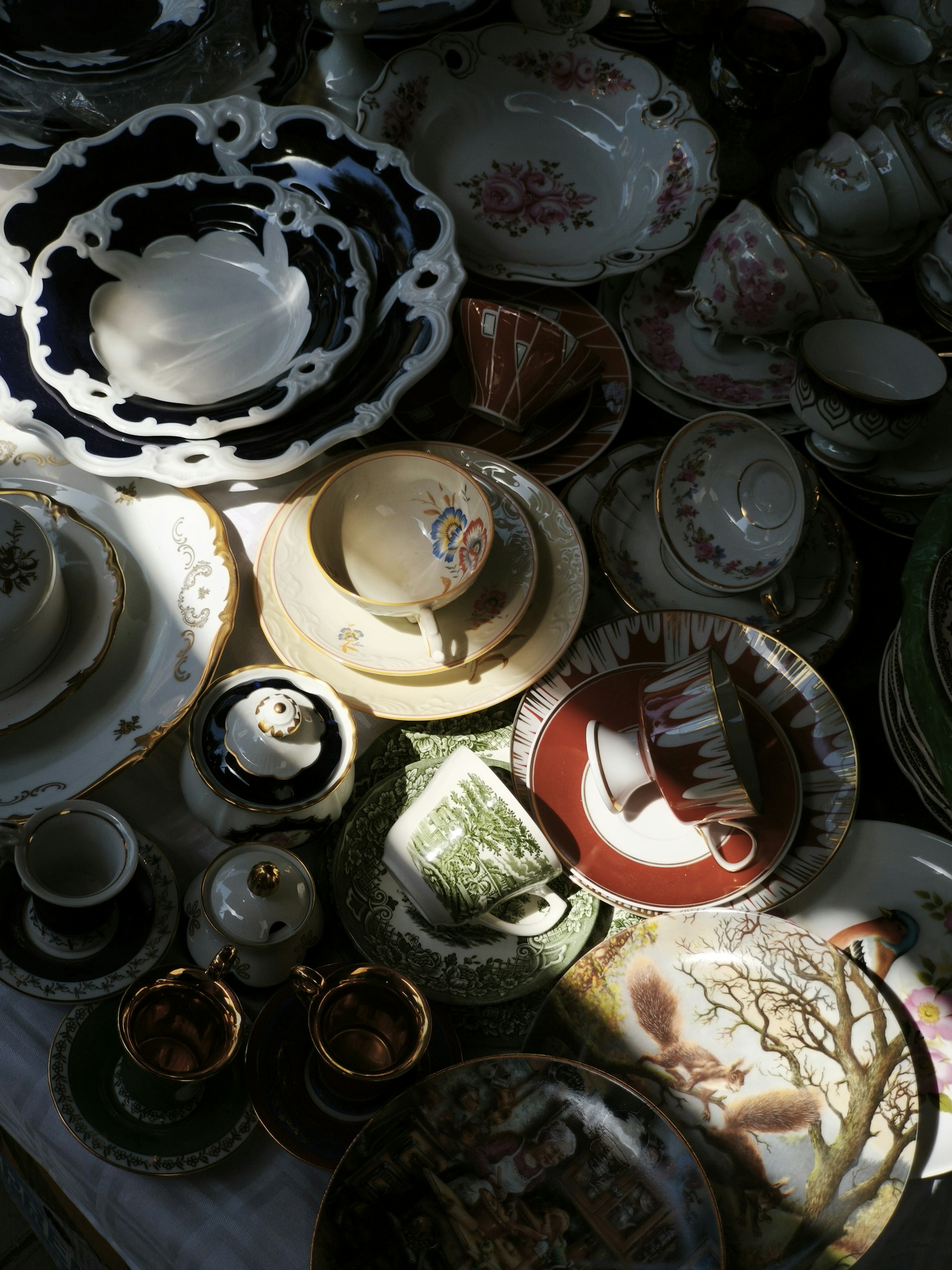 Various vintage teacups and plates are arranged closely together.
