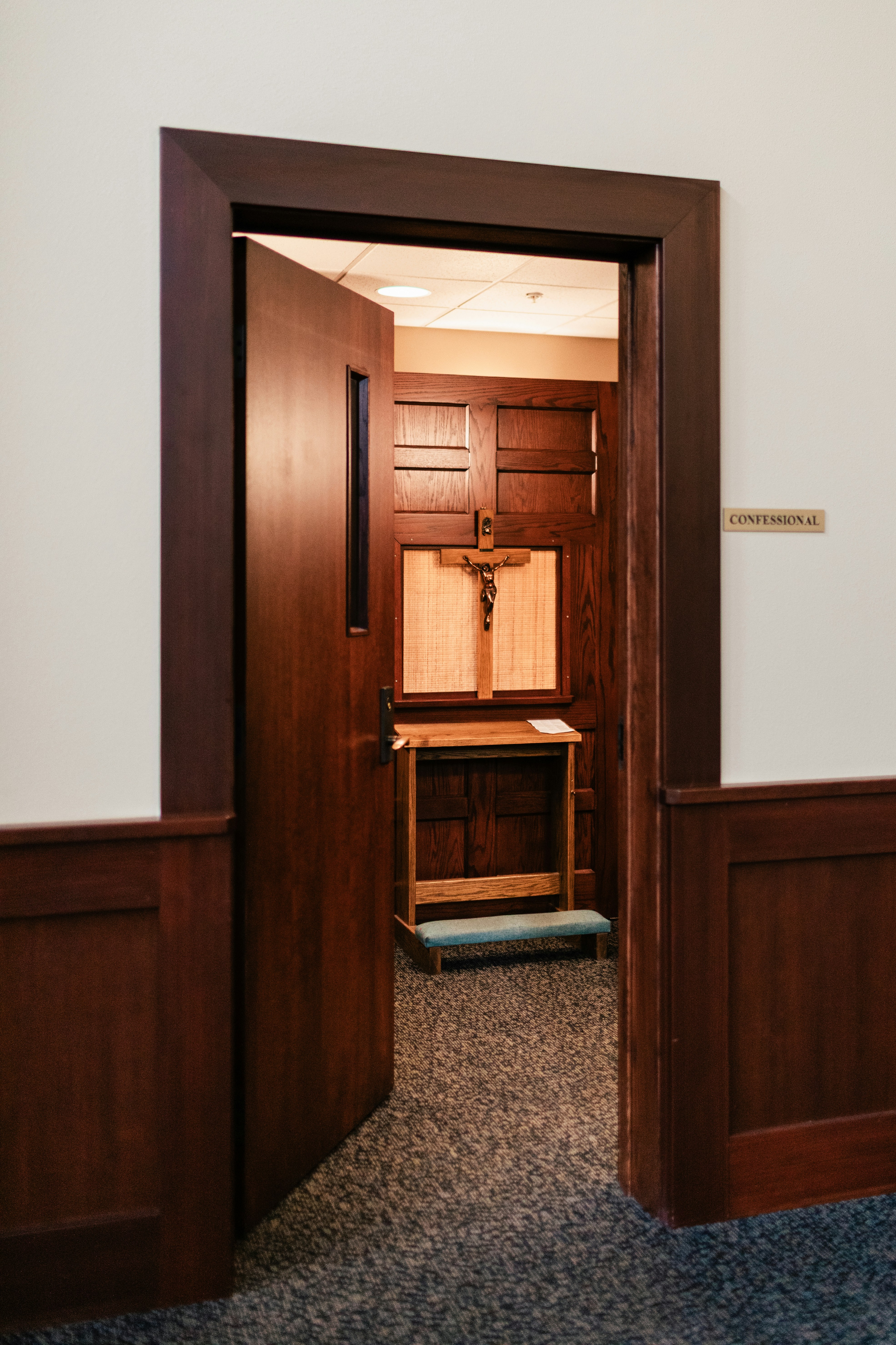 An open door reveals a confessional booth.