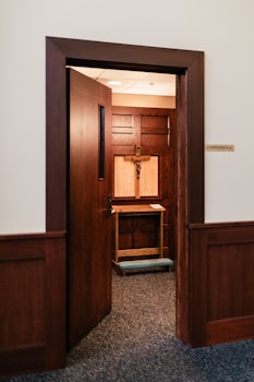 An open door reveals a confessional booth.