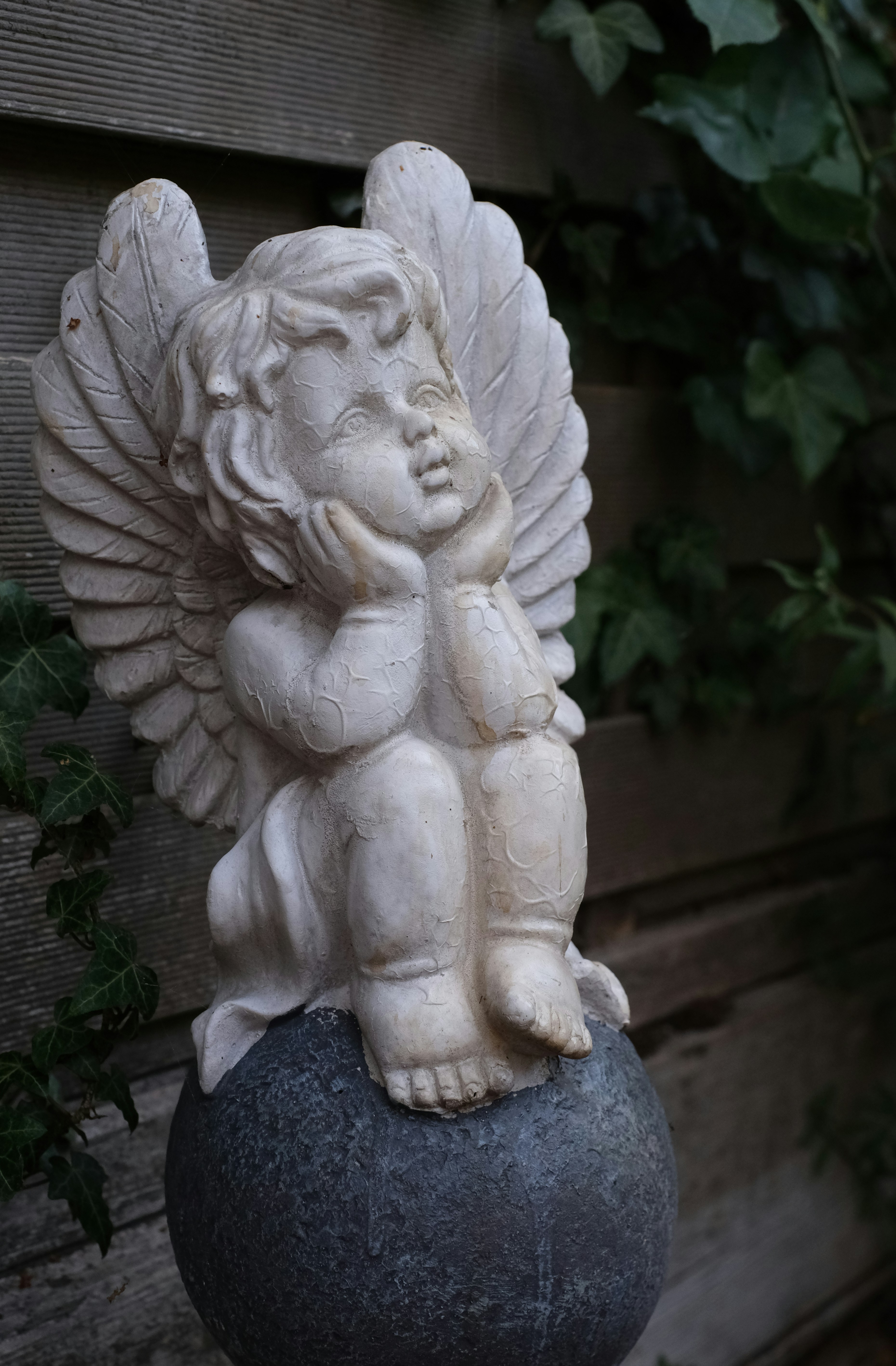 Una statua di angelo cherubino poggia su una palla di pietra.