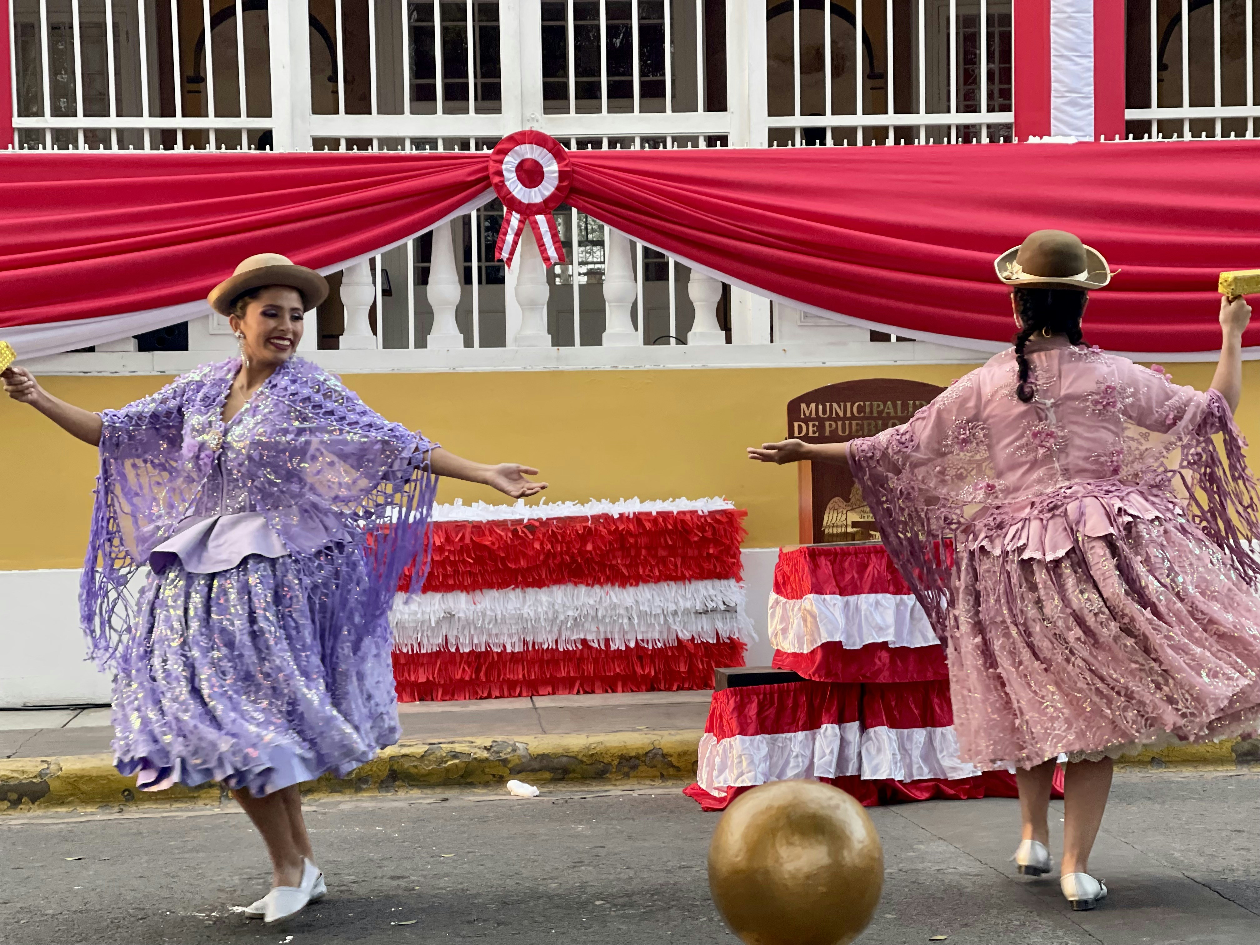 Dos mujeres bailan con coloridos trajes tradicionales.