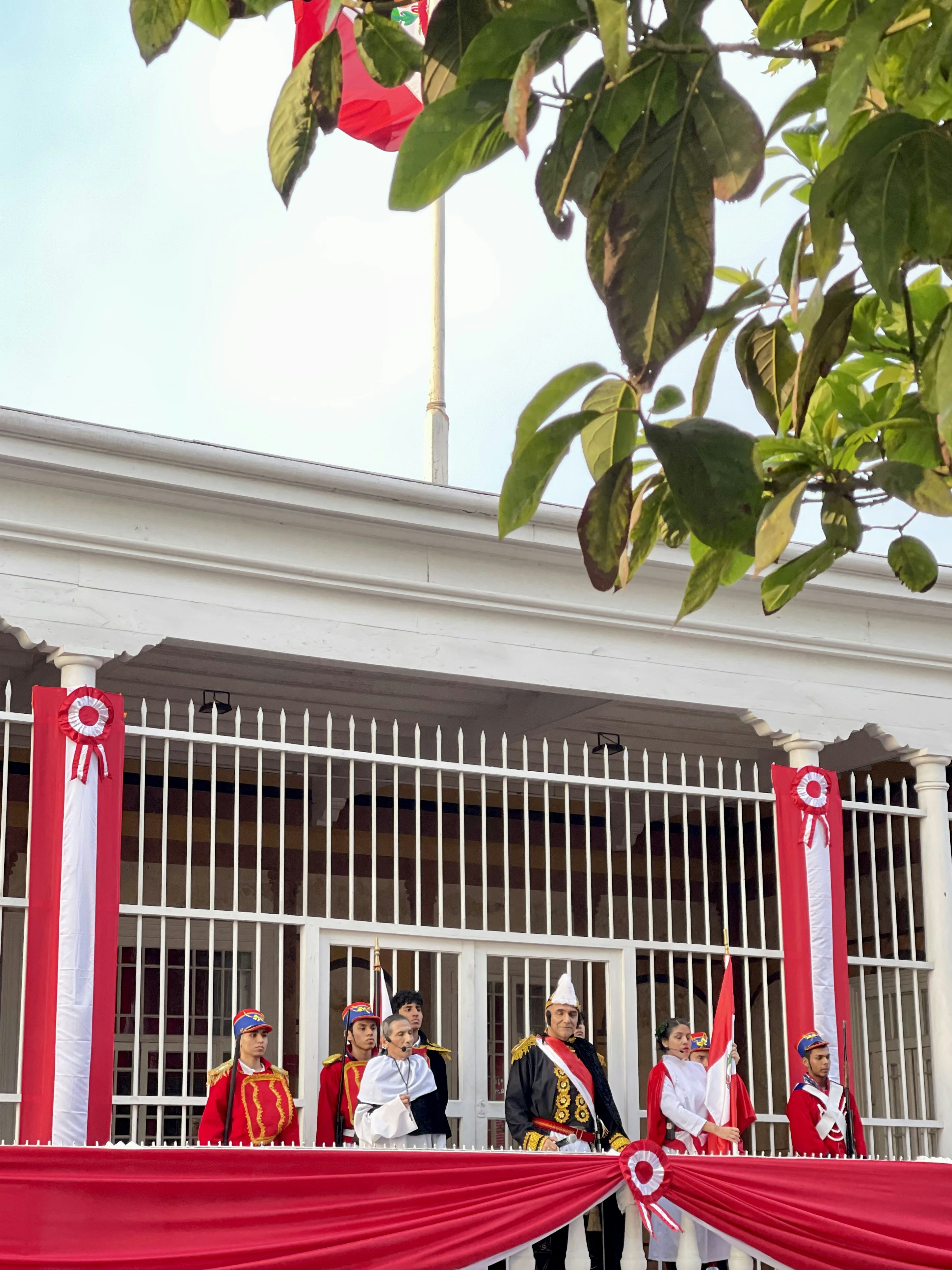 Personas vestidas de ceremonial se paran en un balcón.
