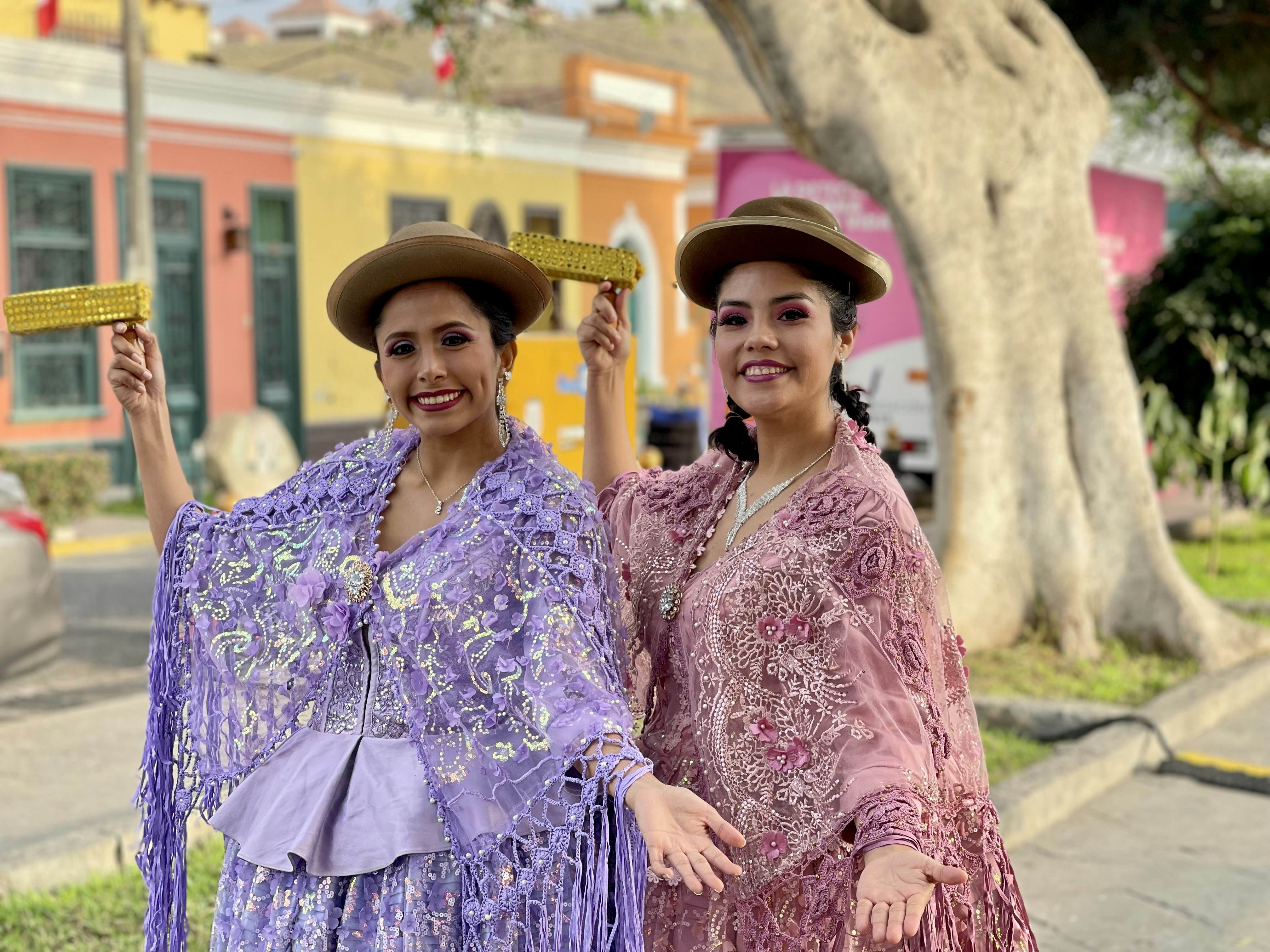 Dos mujeres con vestidos tradicionales posan felices.