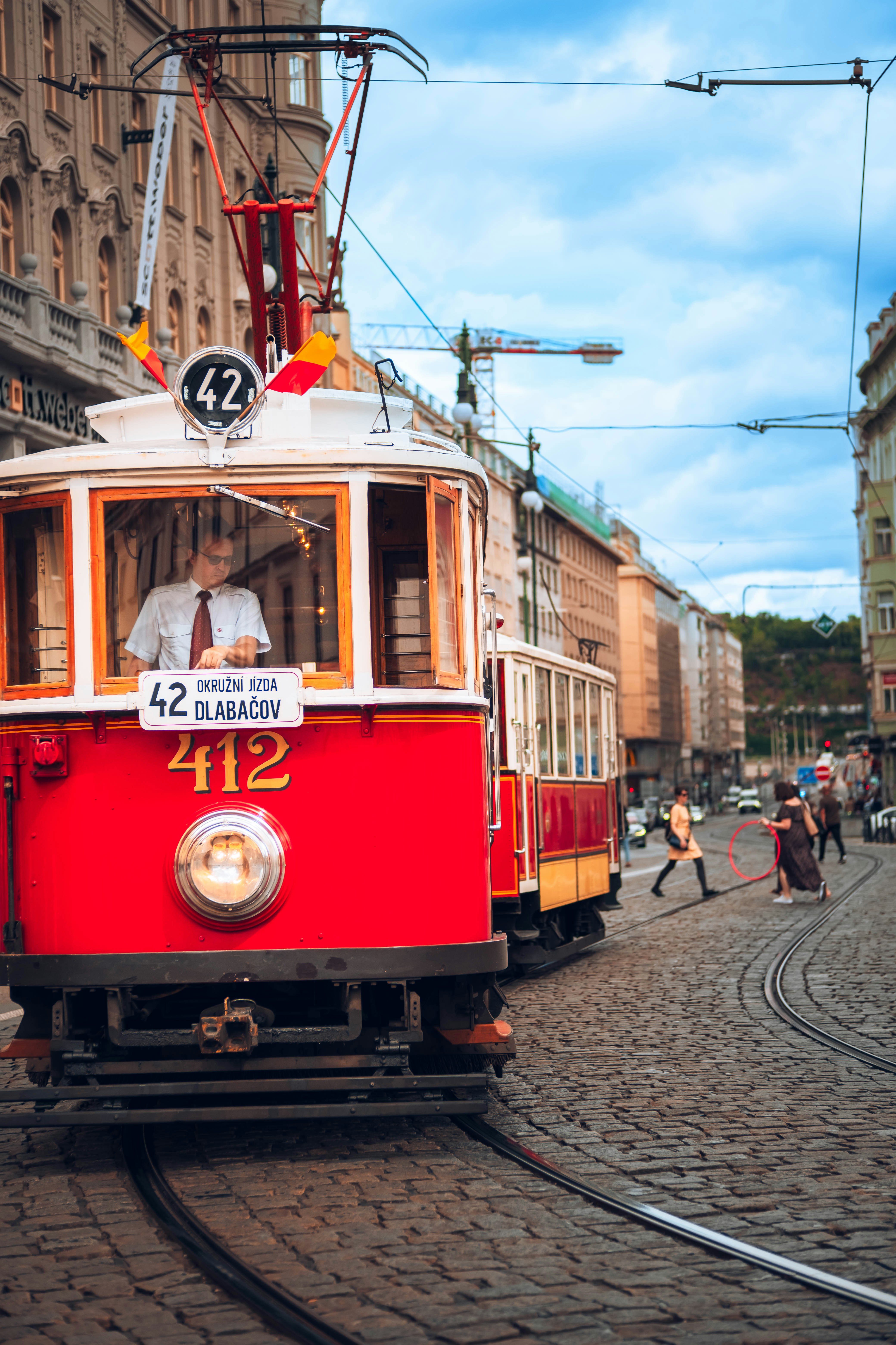 A vintage tram drives down a cobblestone street.