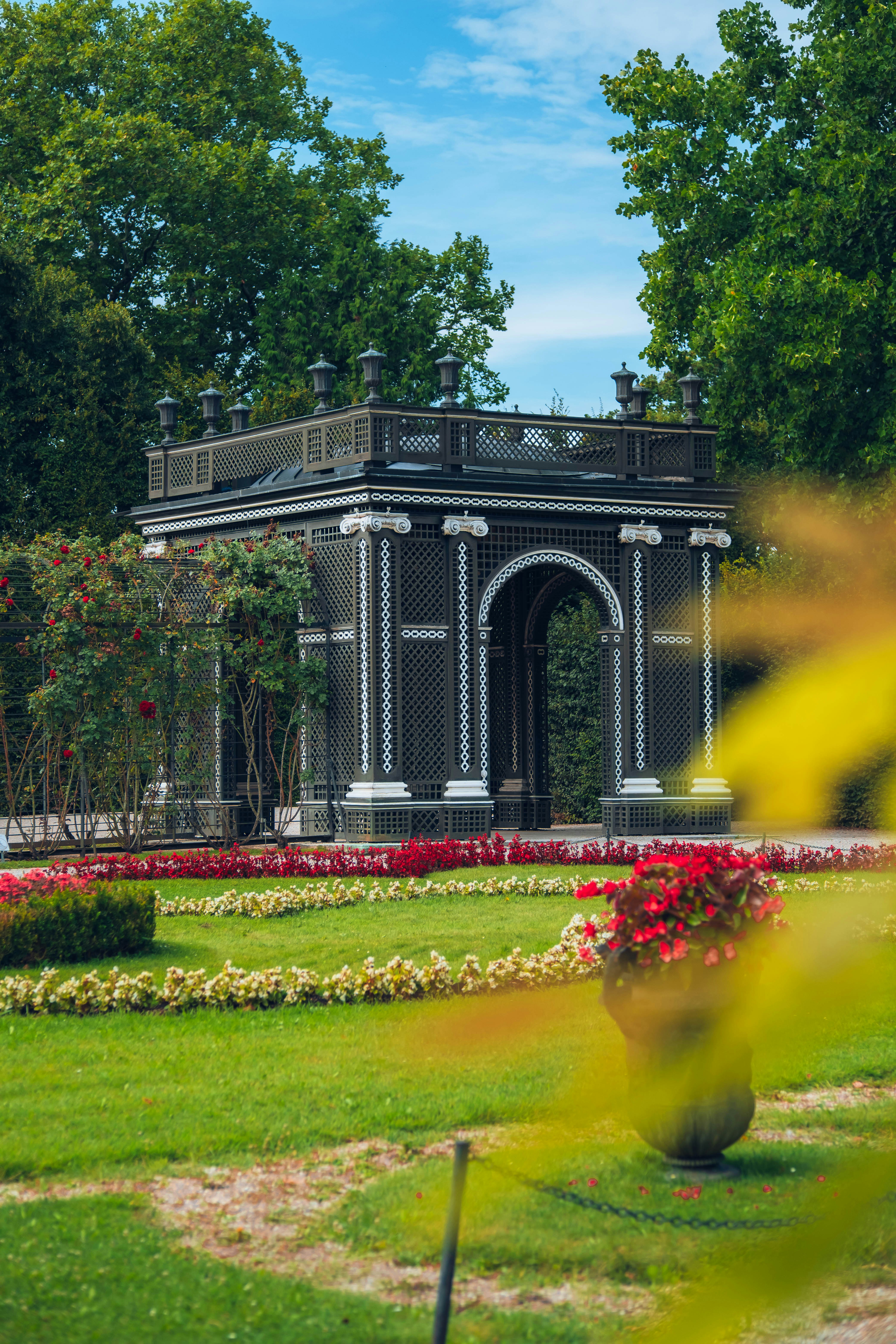 A decorative structure stands in a beautiful garden.