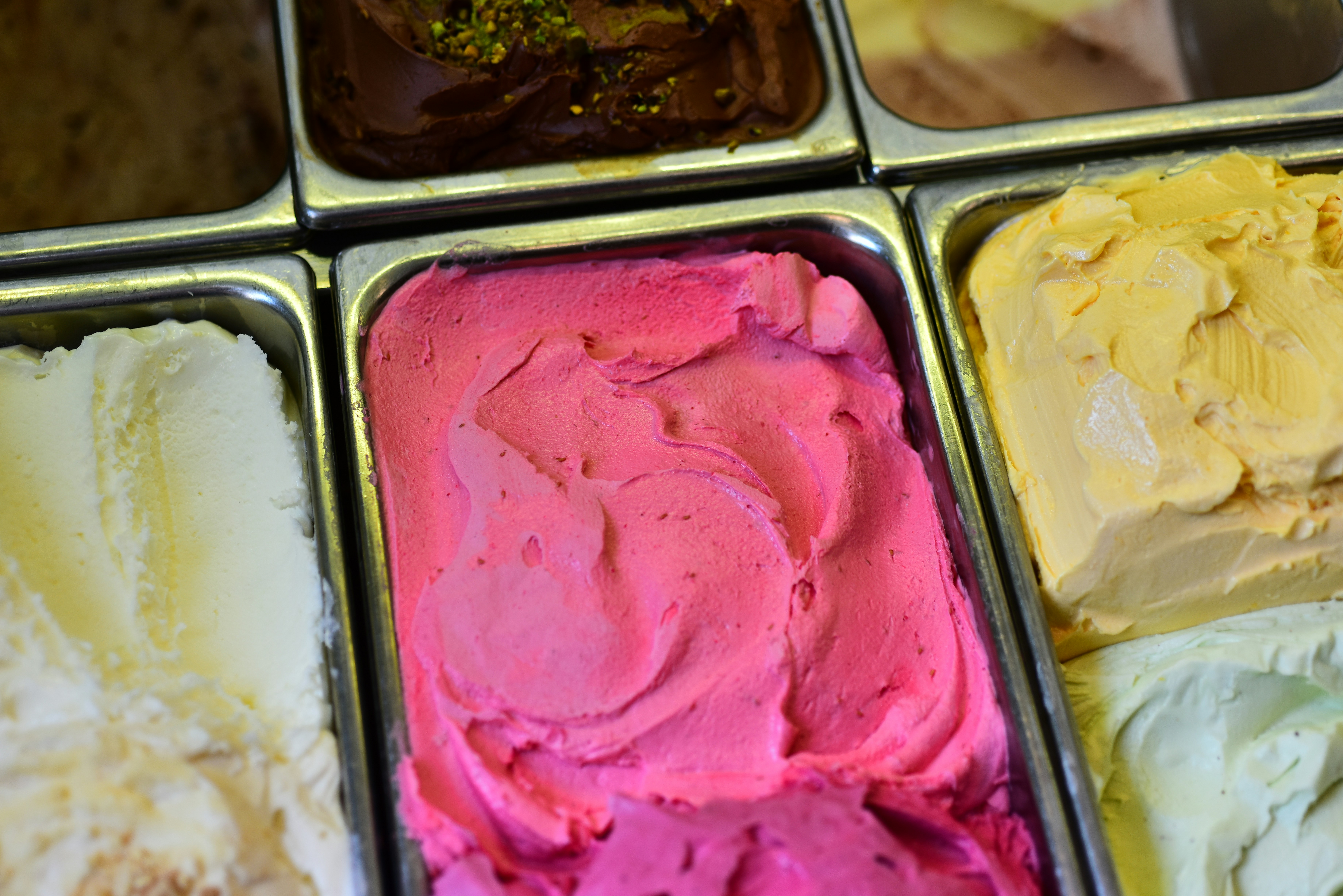 Delicious gelato flavors are displayed in metal containers.