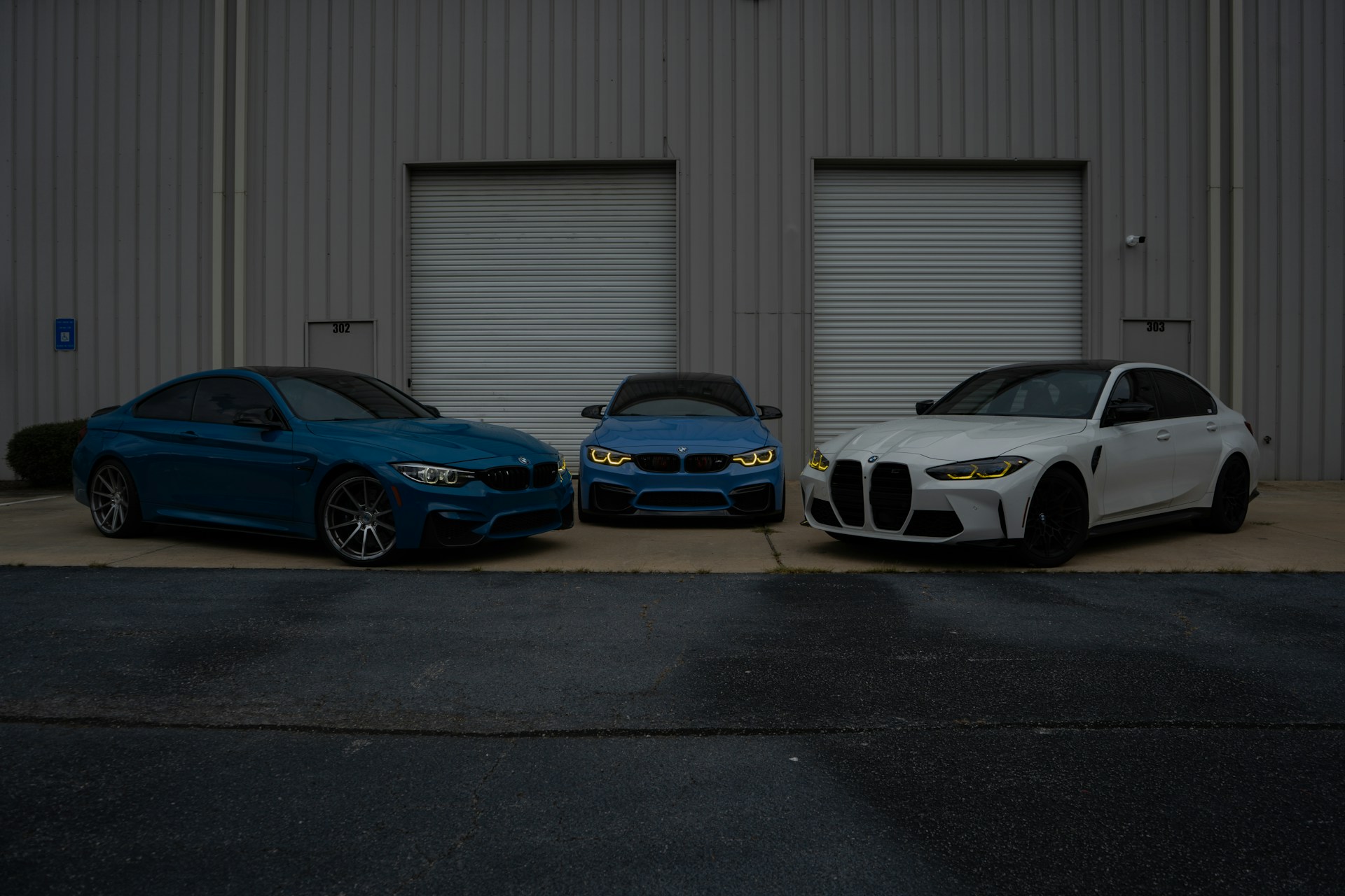 Three BMW cars are parked in front of a building.