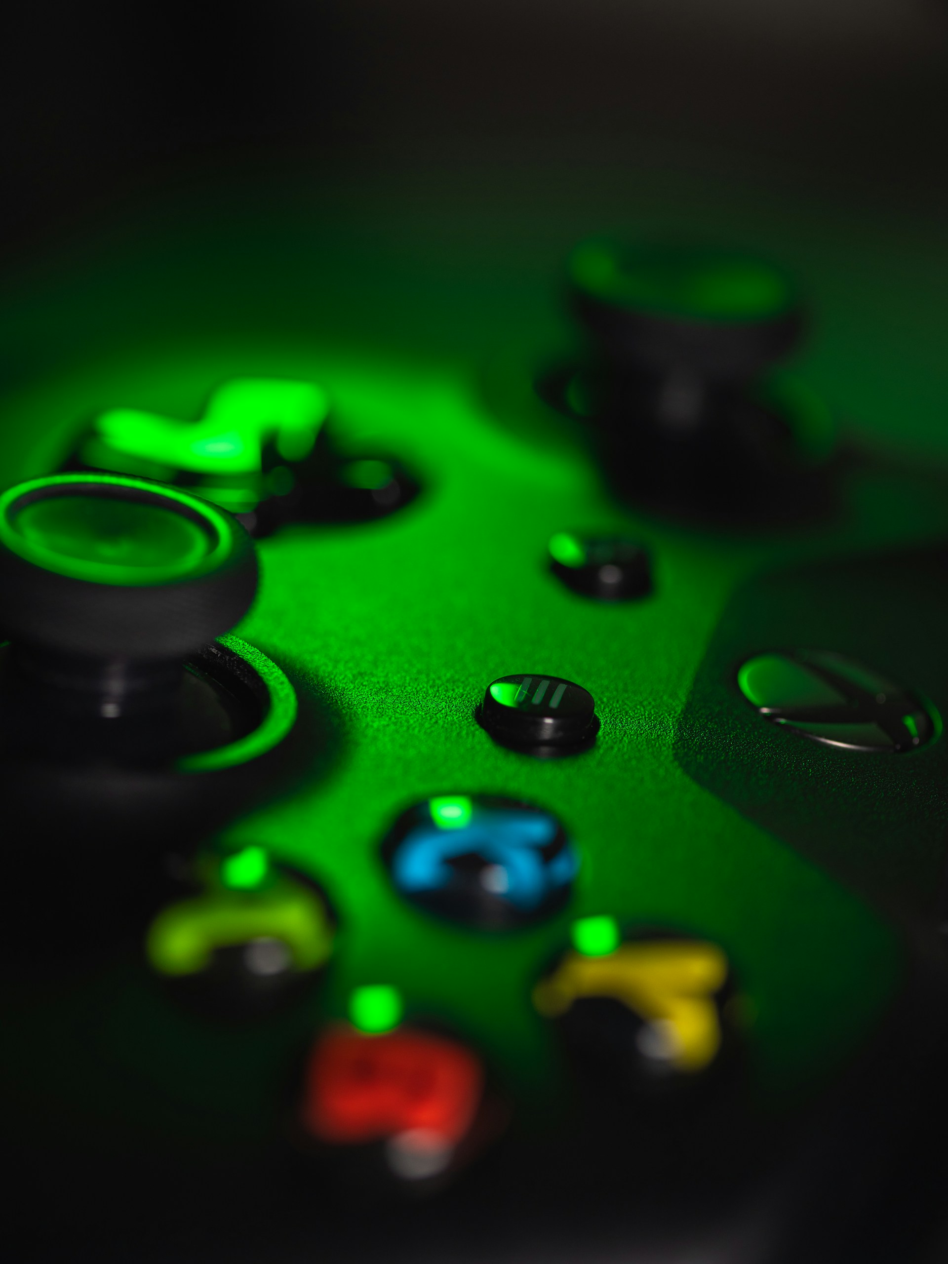 Close-up view of a gaming controller, lit in green.