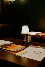 A cozy restaurant table with a lamp is shown.