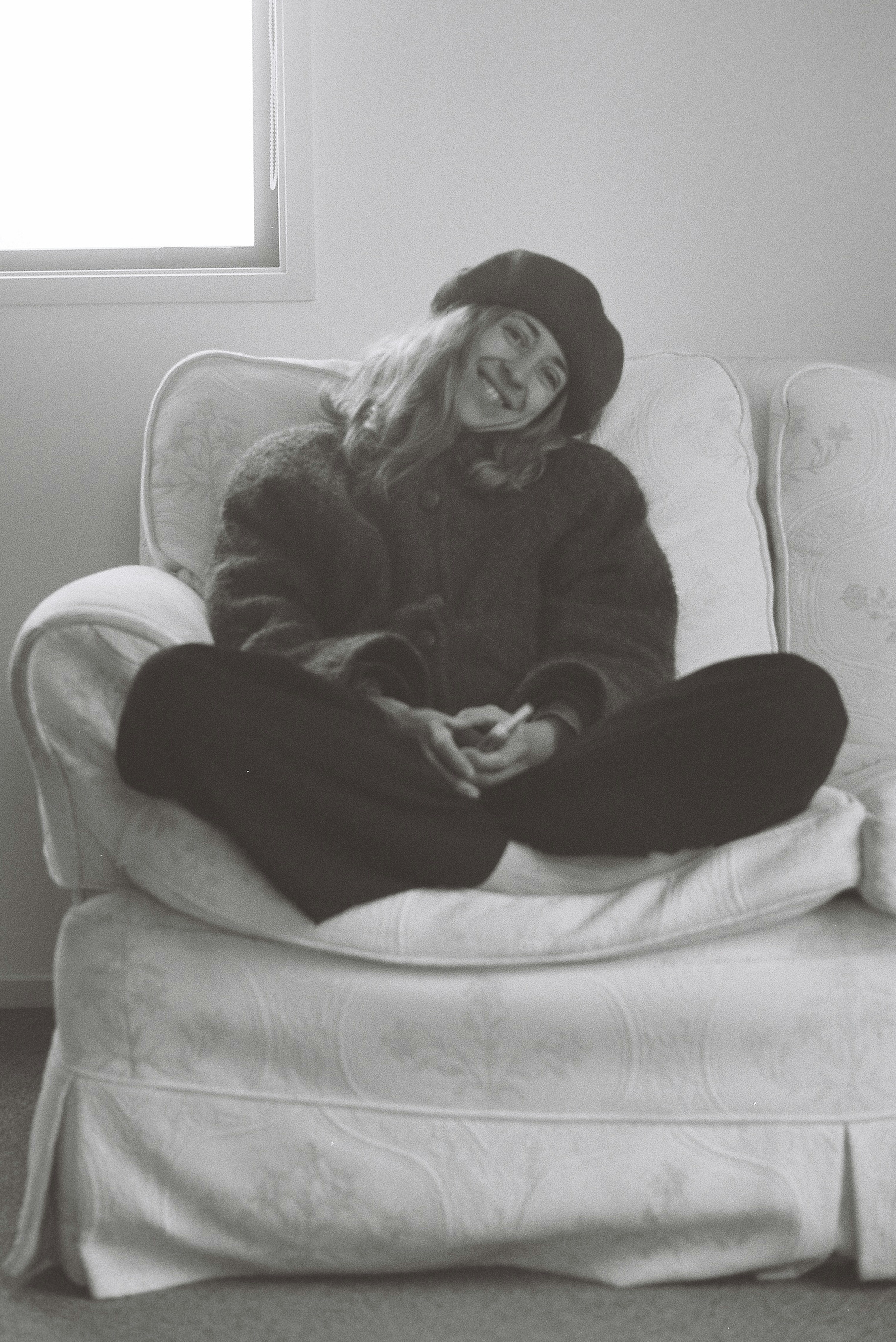 A woman sits smiling on a couch.
