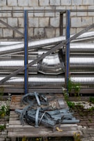 Metal pipes and parts rest against a brick wall.