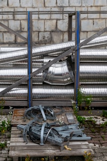 Metal pipes and parts rest against a brick wall.