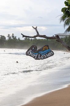 Surf lesson sign hangs above a beach.