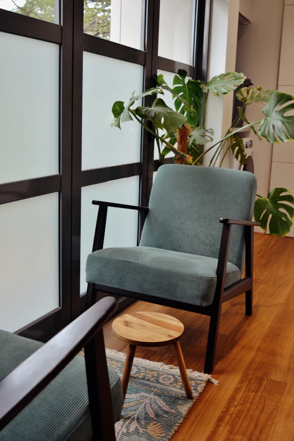 A cozy reading nook with chair and plant.