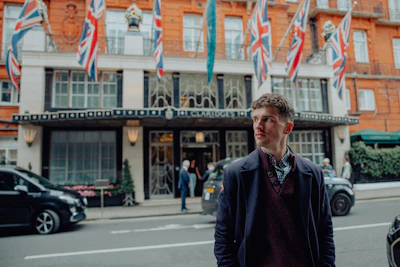 A man stands in front of a building with flags.