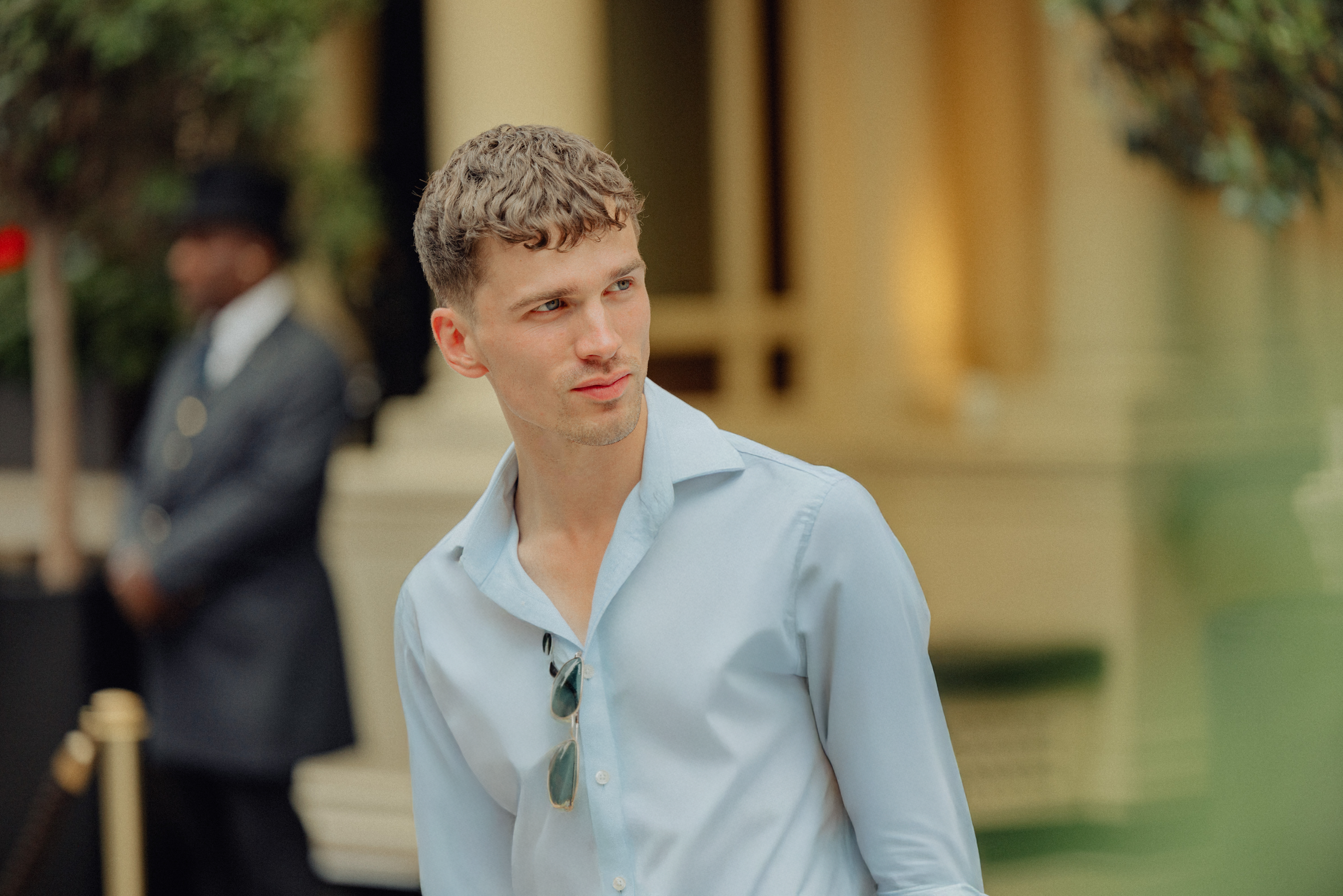 A man is posing outdoors near a building.