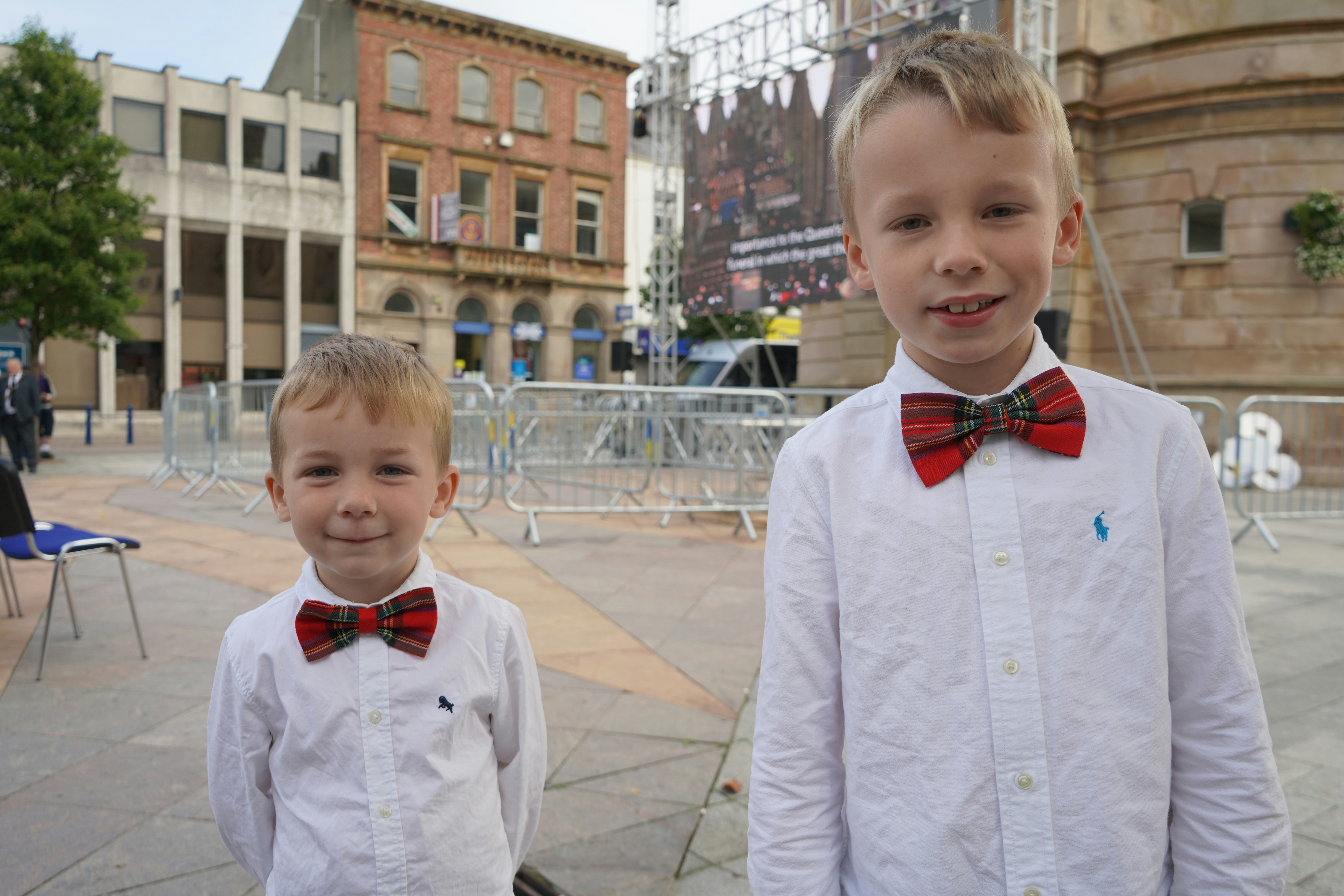 Two young boys stand together, wearing bow ties.