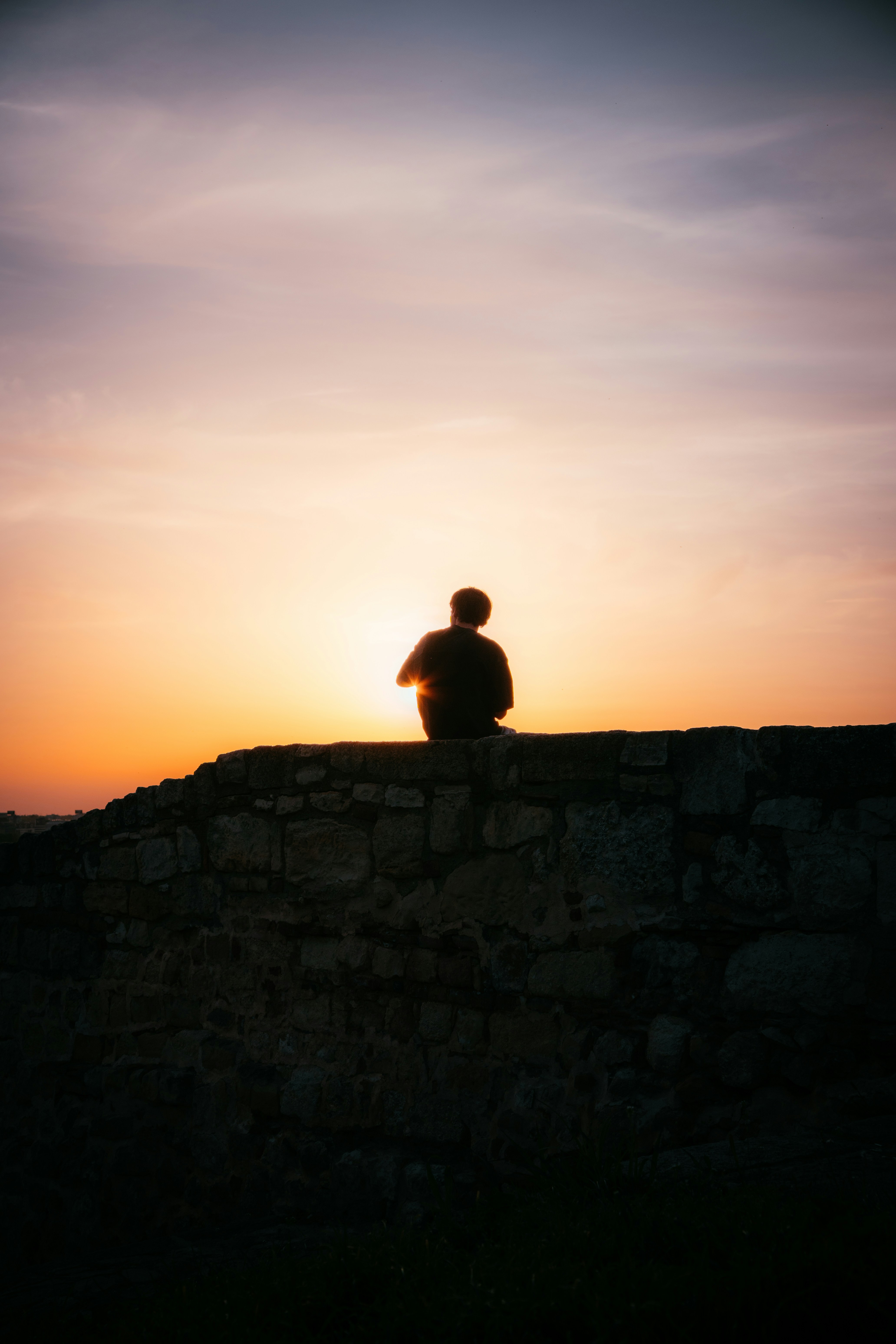 A person watches sunset over a wall.