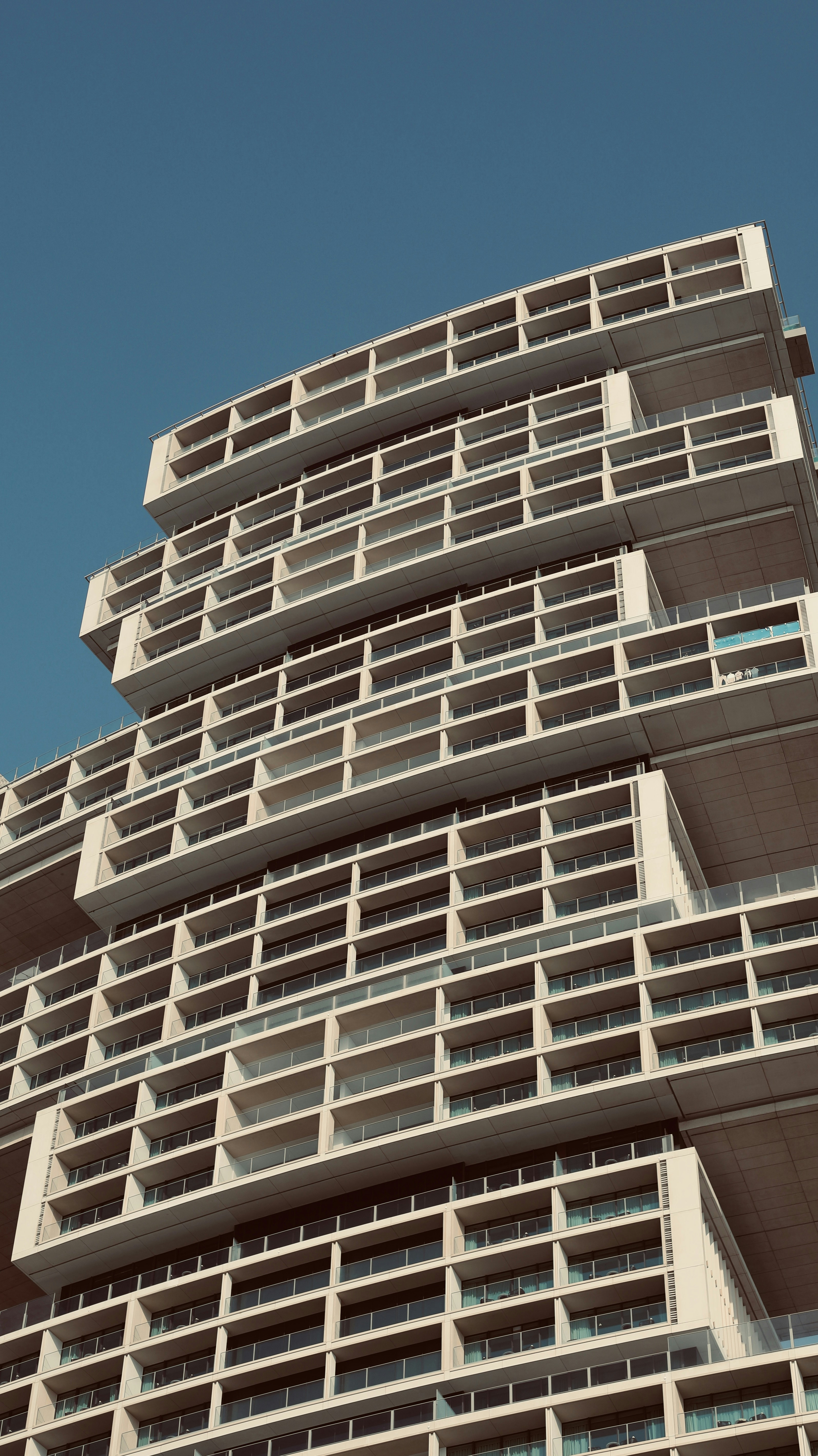 Un edificio moderno con muchos balcones contra un cielo azul.