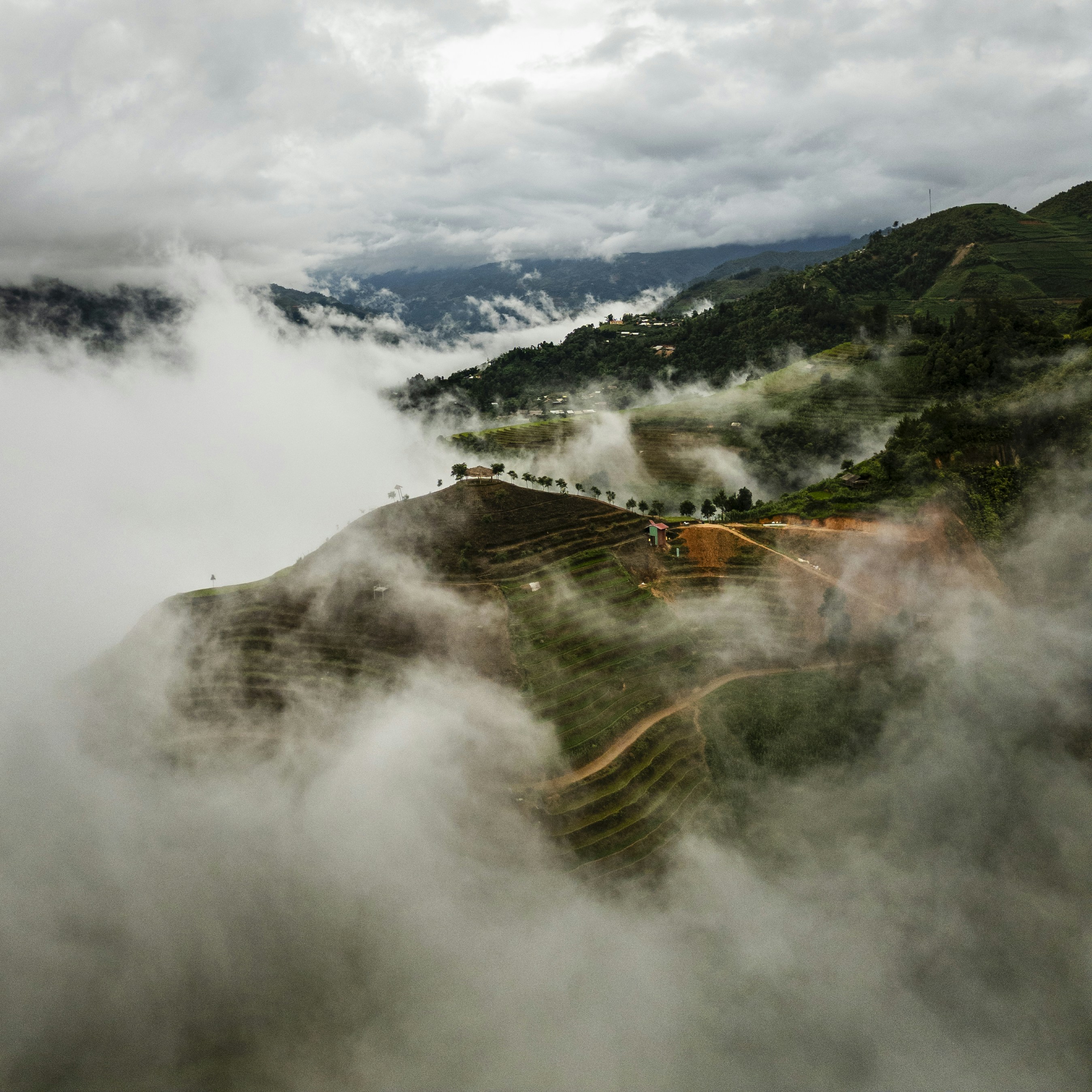 Clouds engulf green mountains and a valley.