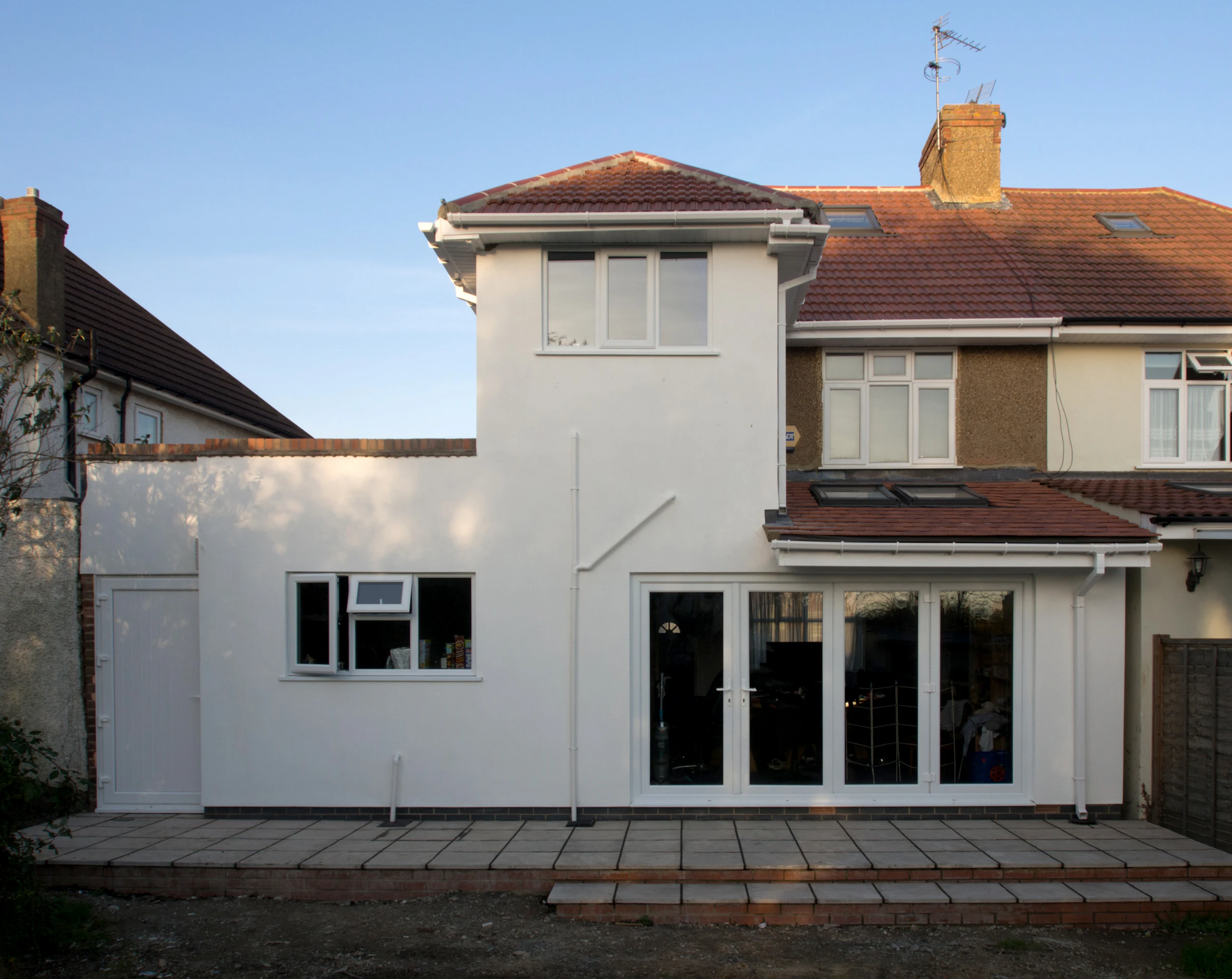 A modern home extension with tall glass walls opening onto a garden
