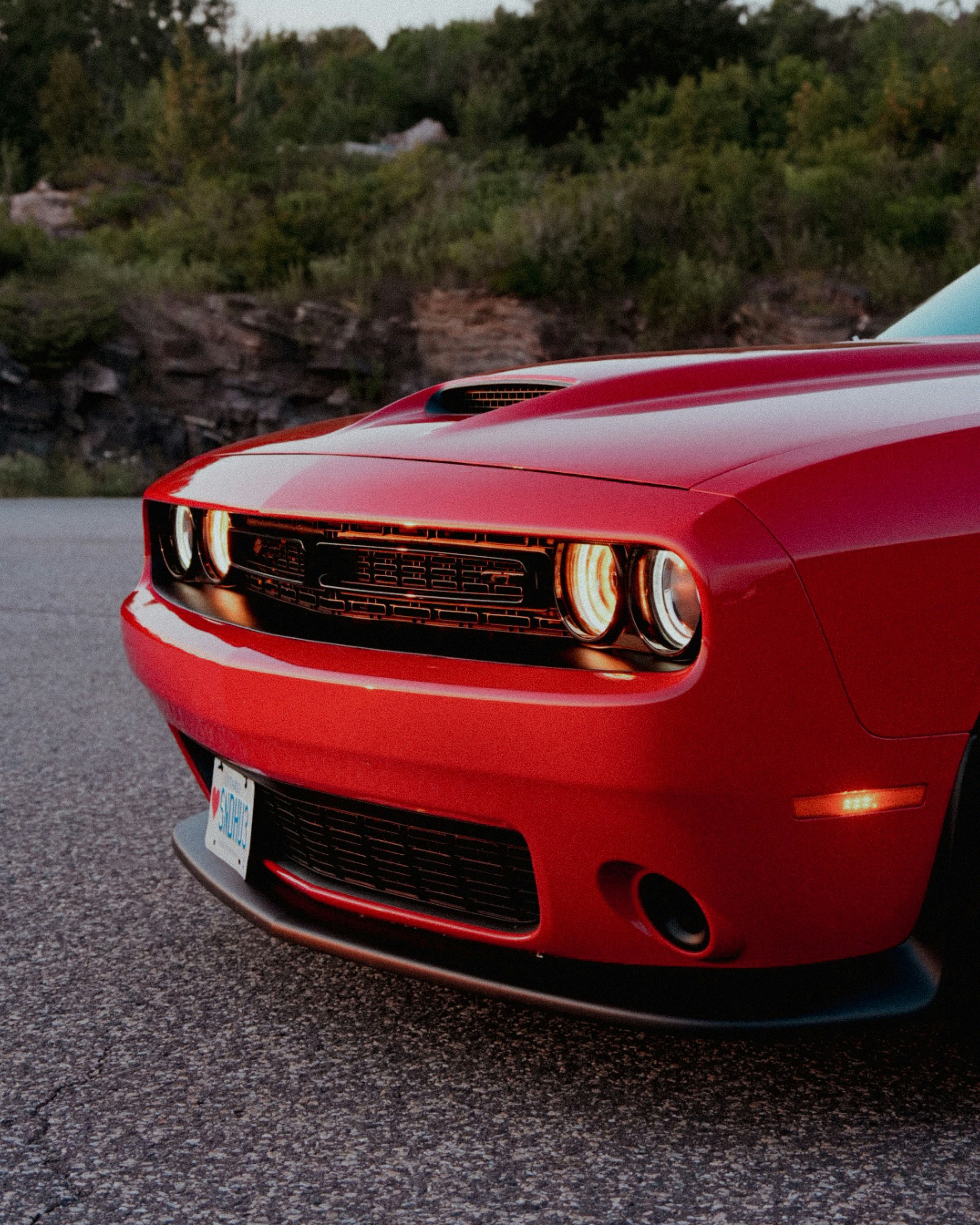 A red dodge challenger shows off its front.