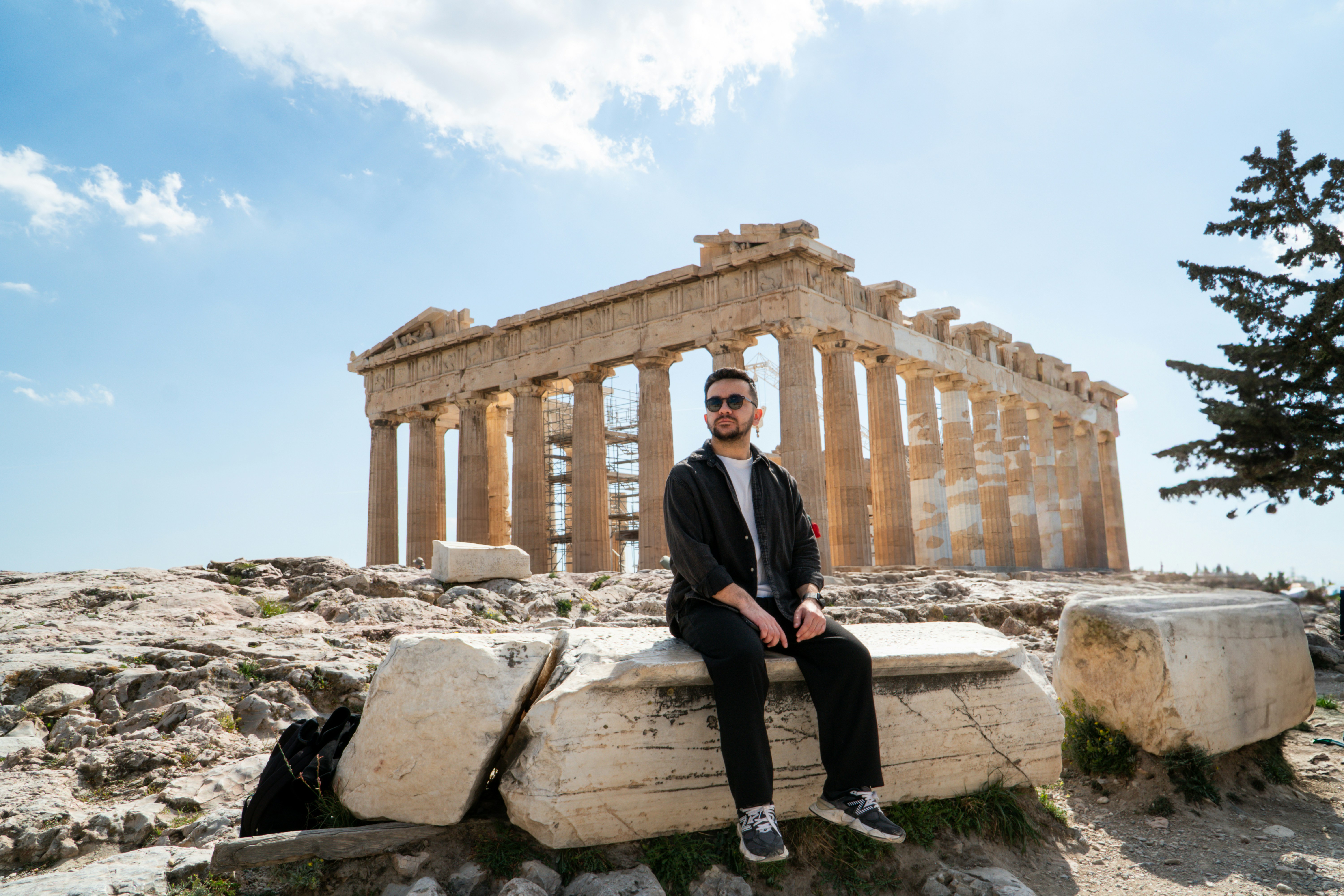Man poses in front of the parthenon in athens.