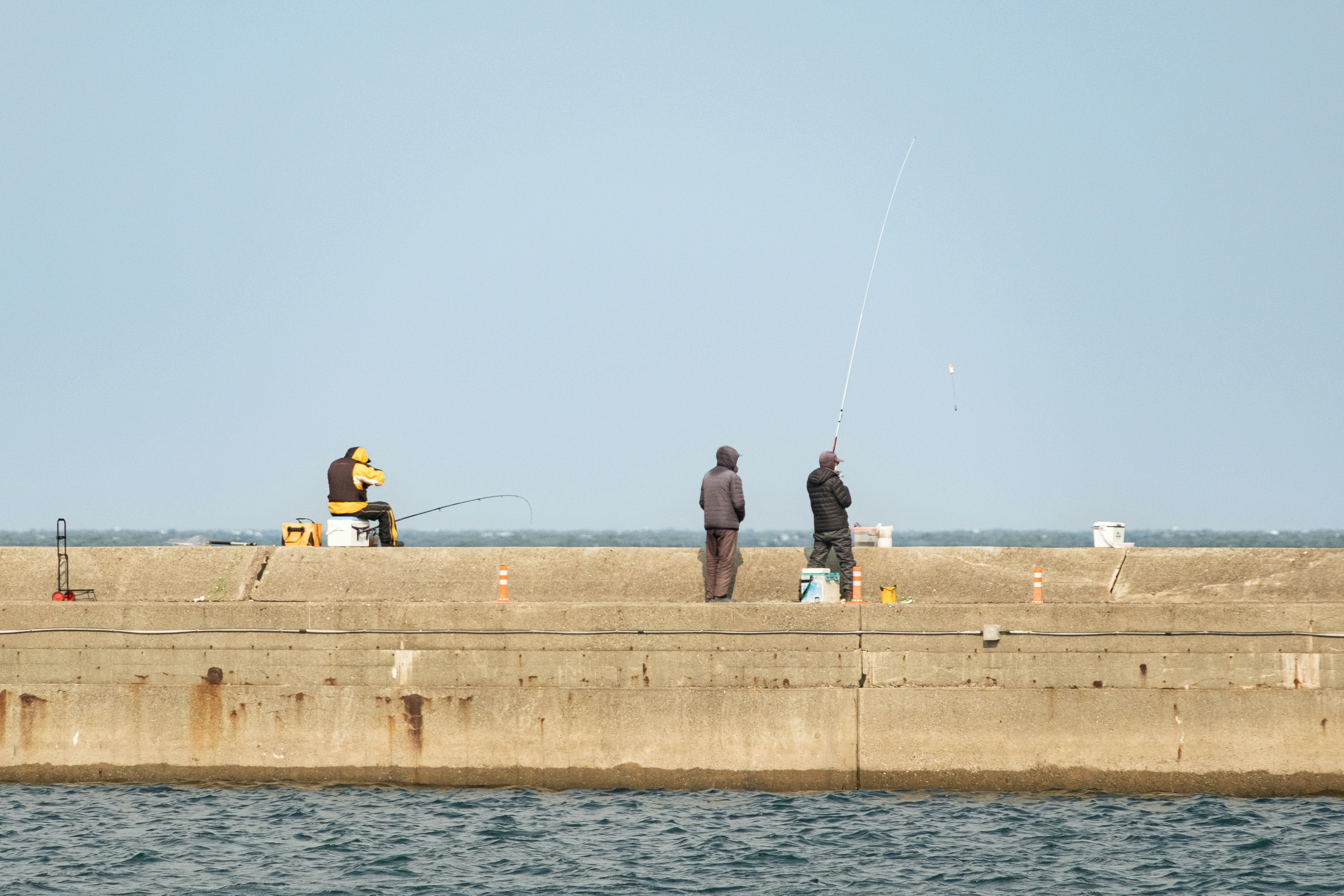 People are fishing from a concrete pier.