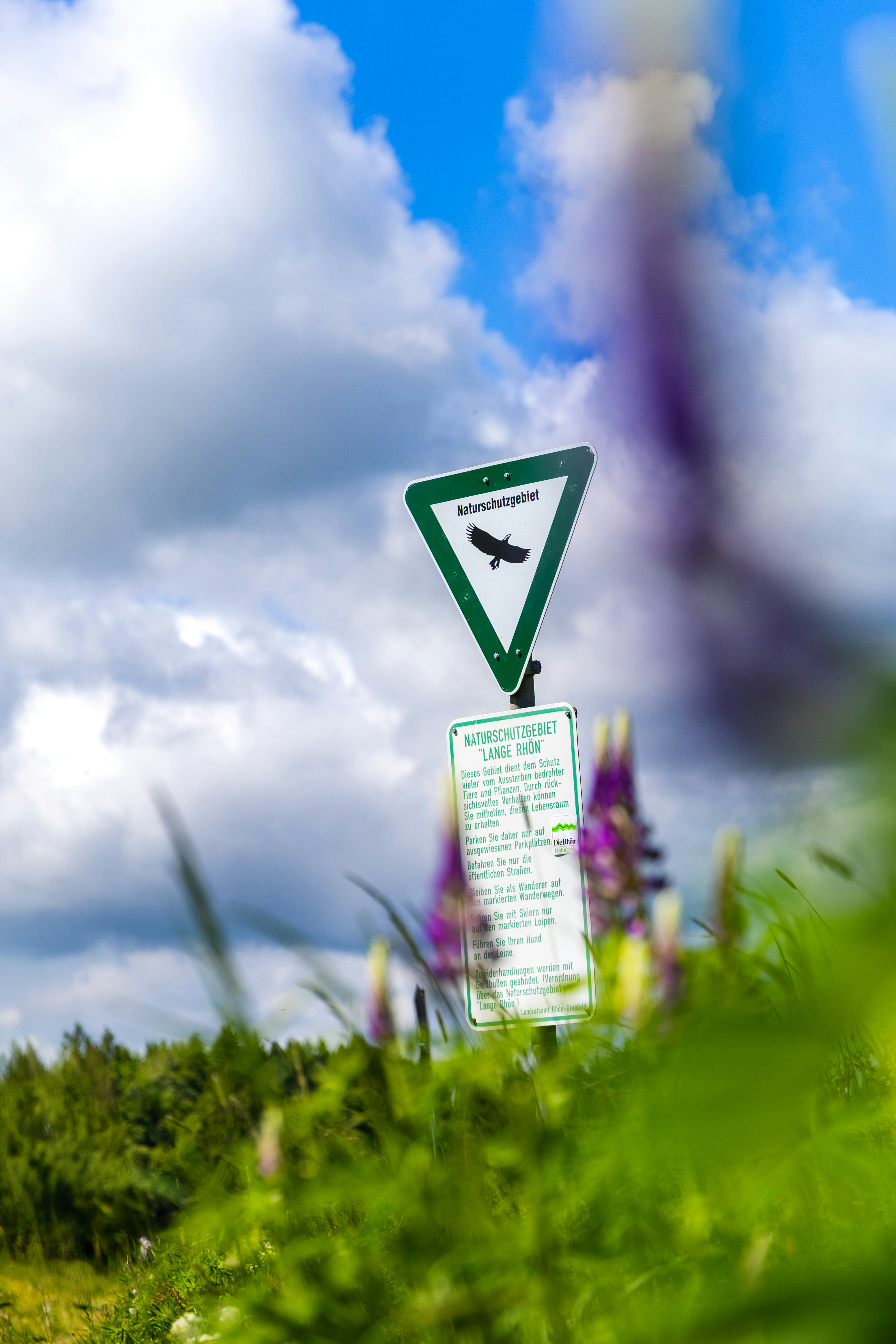 Sign in a nature preserve with flowers.