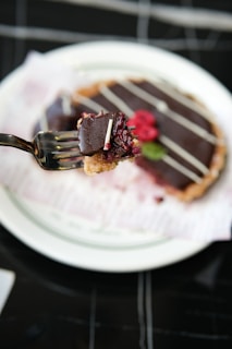 A fork holds a bite of delicious chocolate tart.