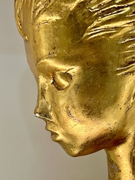 A gold sculpture shows the profile of a face.
