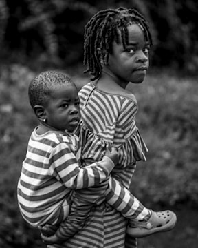 A girl carries a younger child on her back.