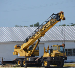 Yellow crane stands tall against a white building.