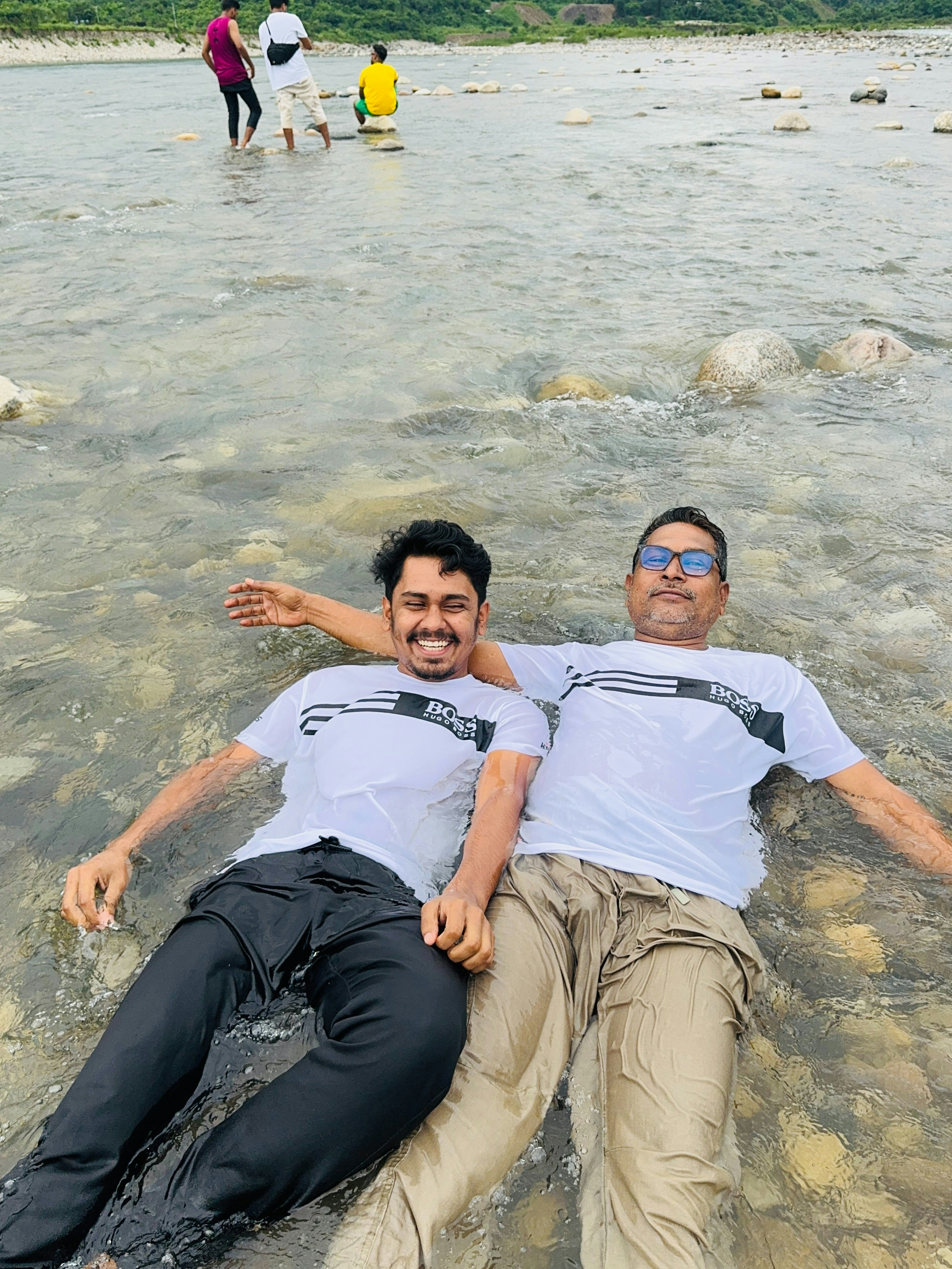 Two men relaxing in shallow river water.