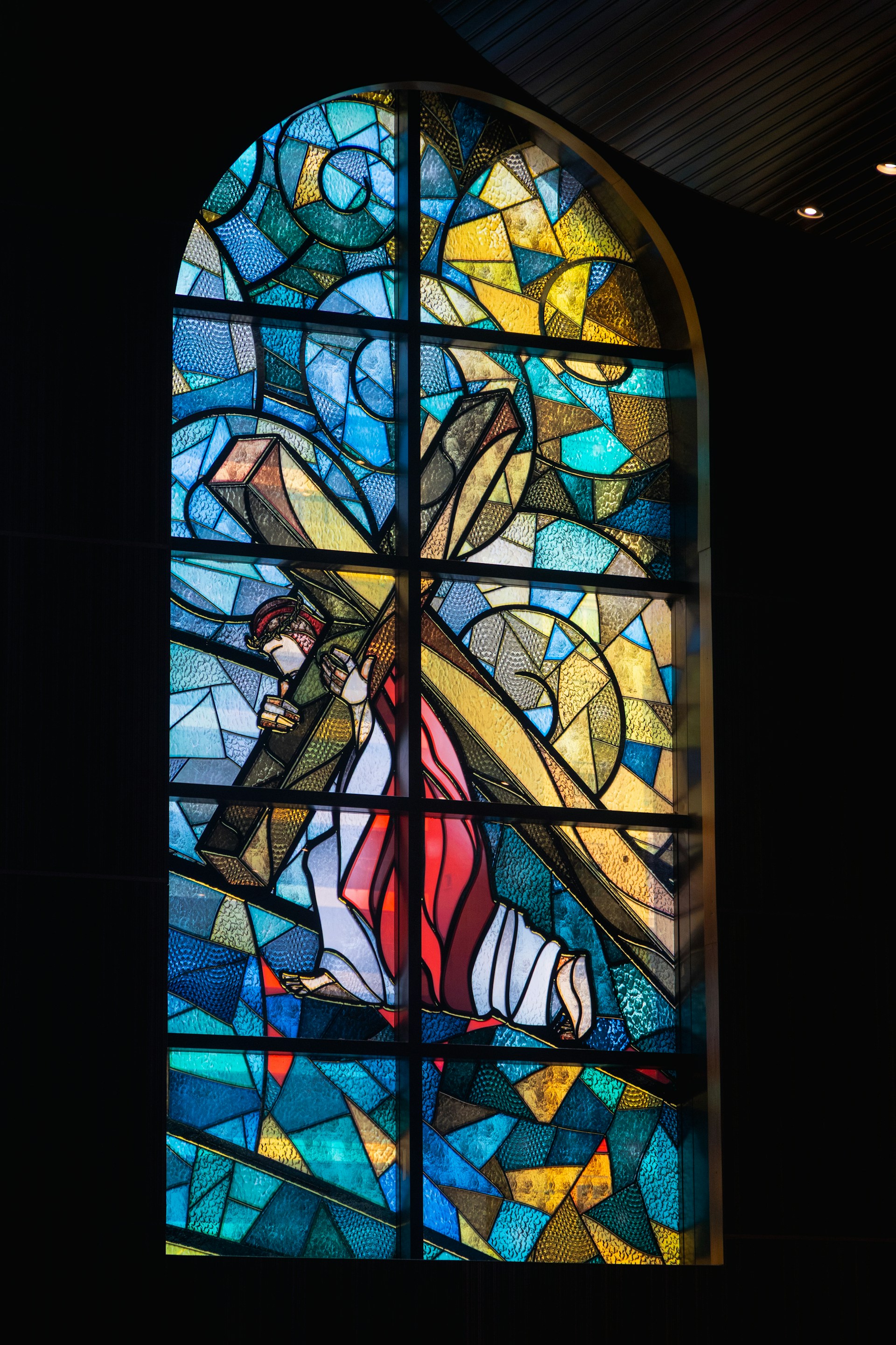 Jesus christ carries the cross in this stained-glass window.