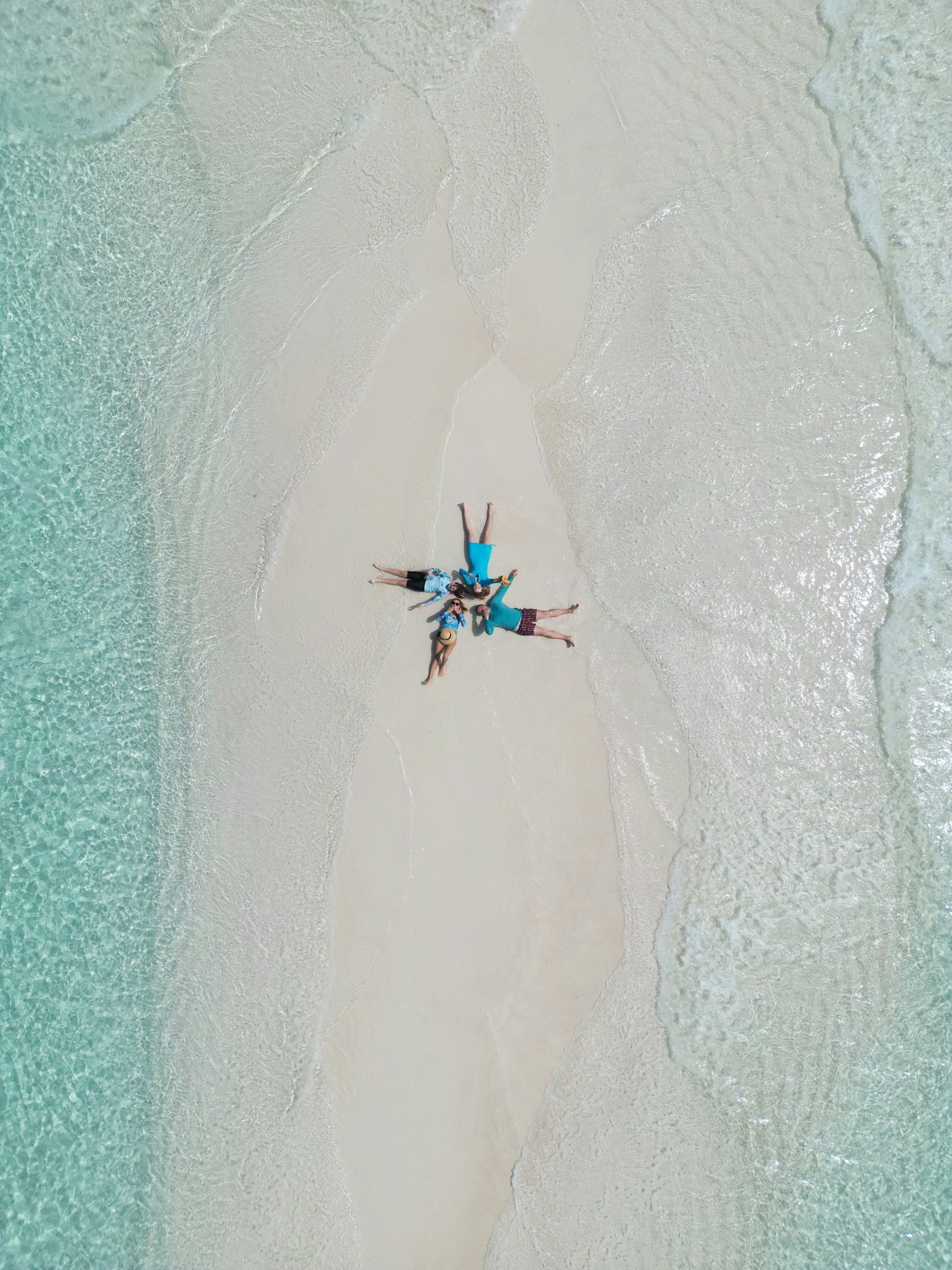 A group of people laying on a sandbar.