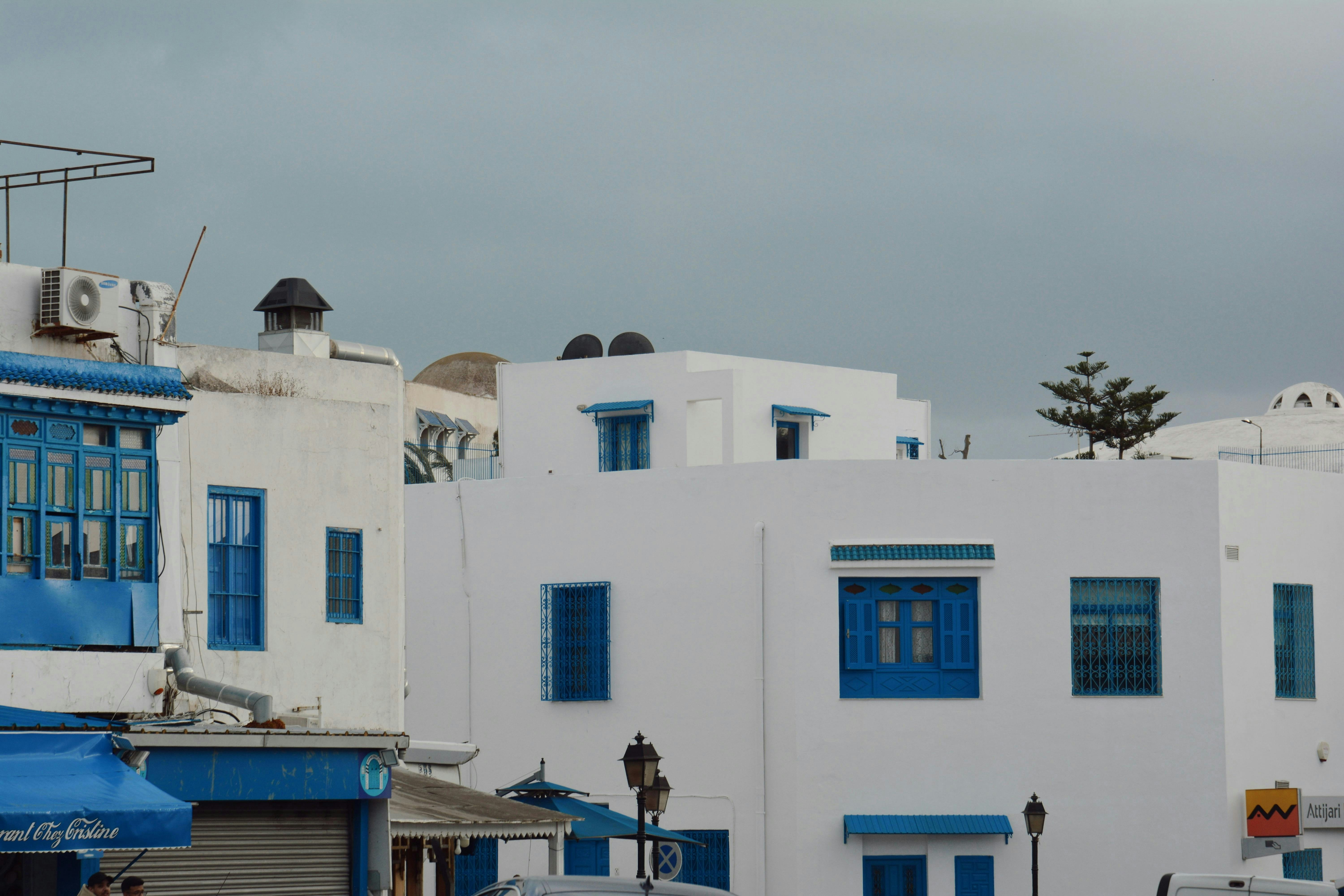 White buildings with blue accents under a cloudy sky.
