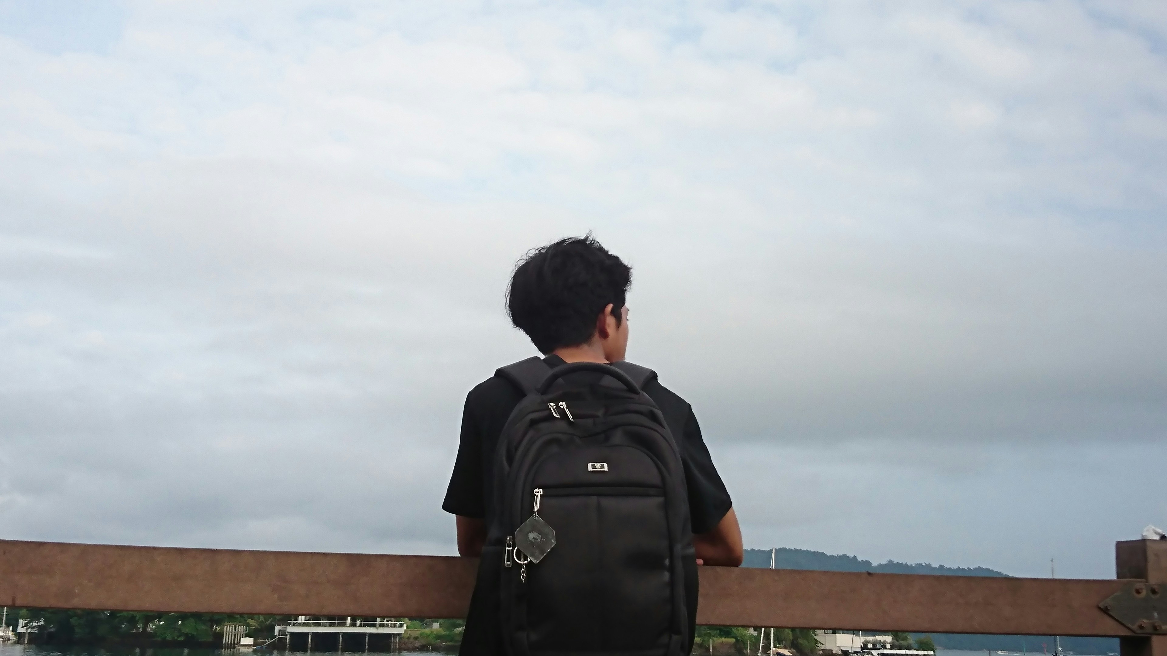 A person with a backpack looks out at the sky.